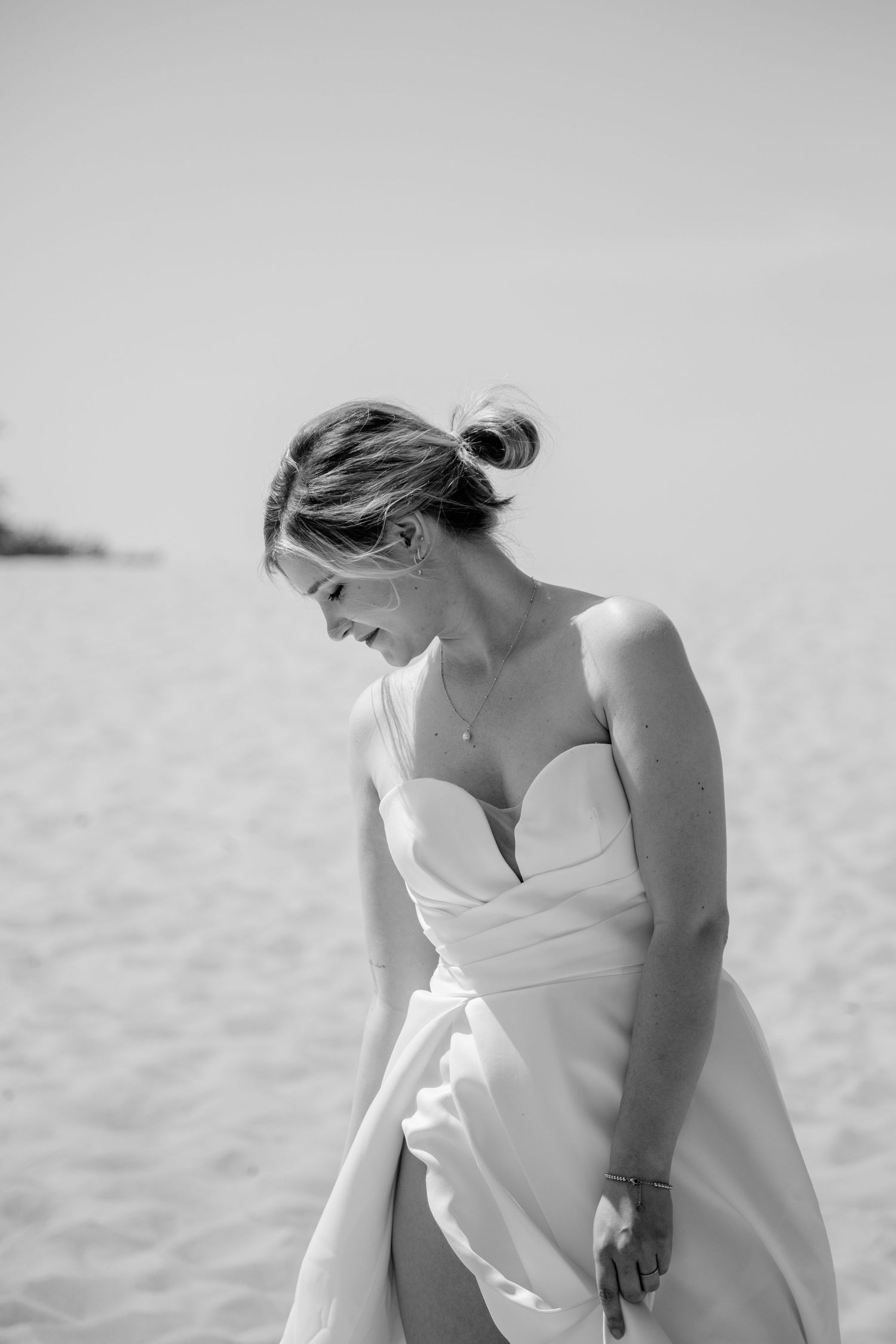 Black and white portrait of someone in a simple elegant wedding dress on a beach.
