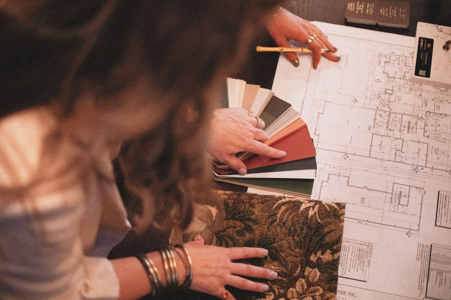Interior designer reviewing fabric swatches and architectural blueprints while holding a pencil.