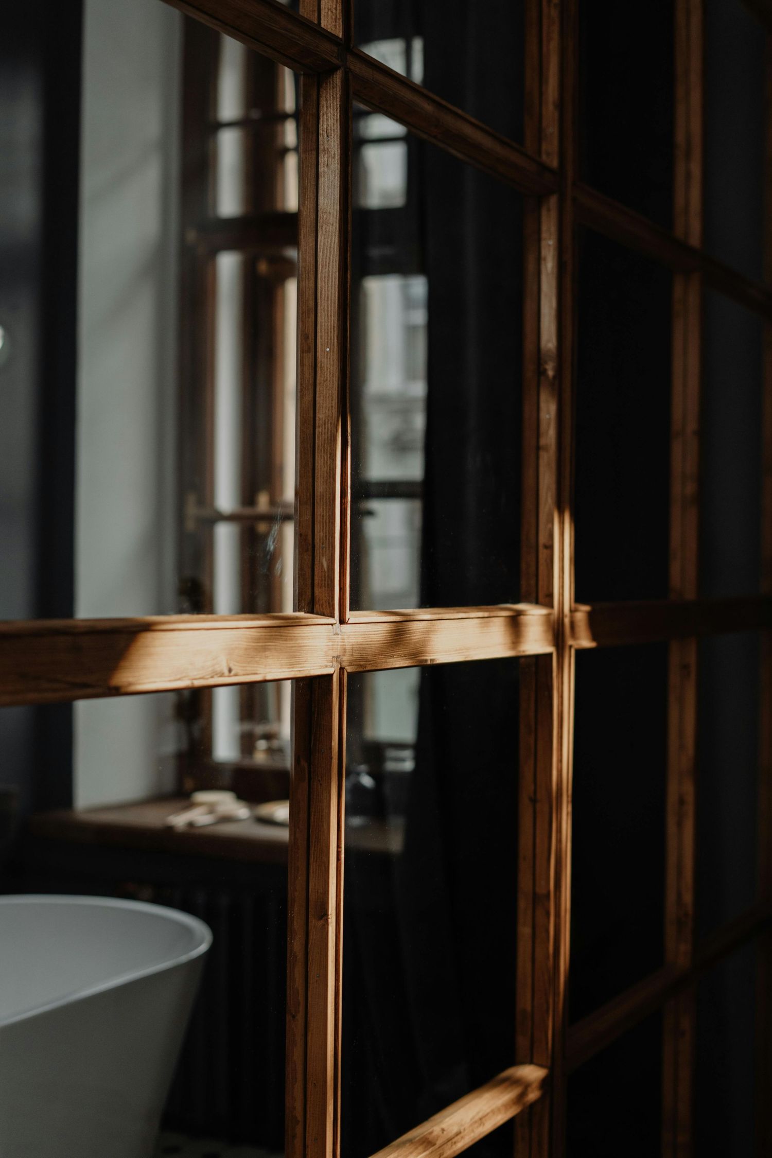 Wooden shelving unit with vertical slats creates geometric patterns in minimalist interior.
