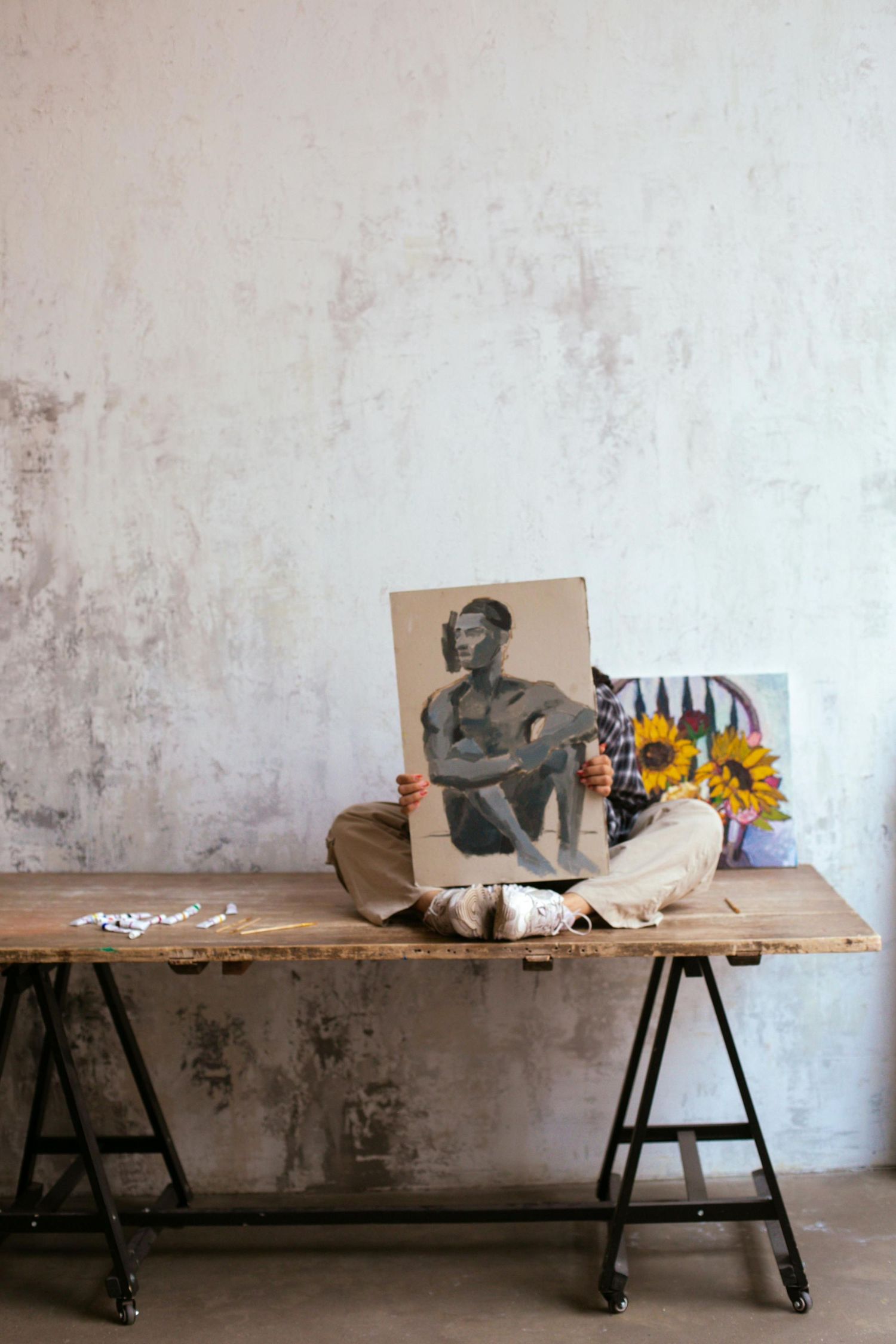 Vintage photograph and sunflowers displayed on rustic wooden table against distressed white wall.