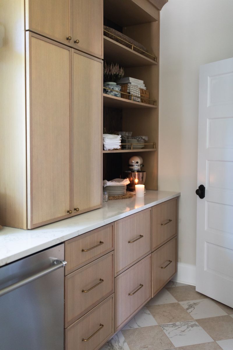 Modern built-in cabinetry with light wood finish, marble countertop, open shelving, and a lit candle in an elegant butler's pantry.