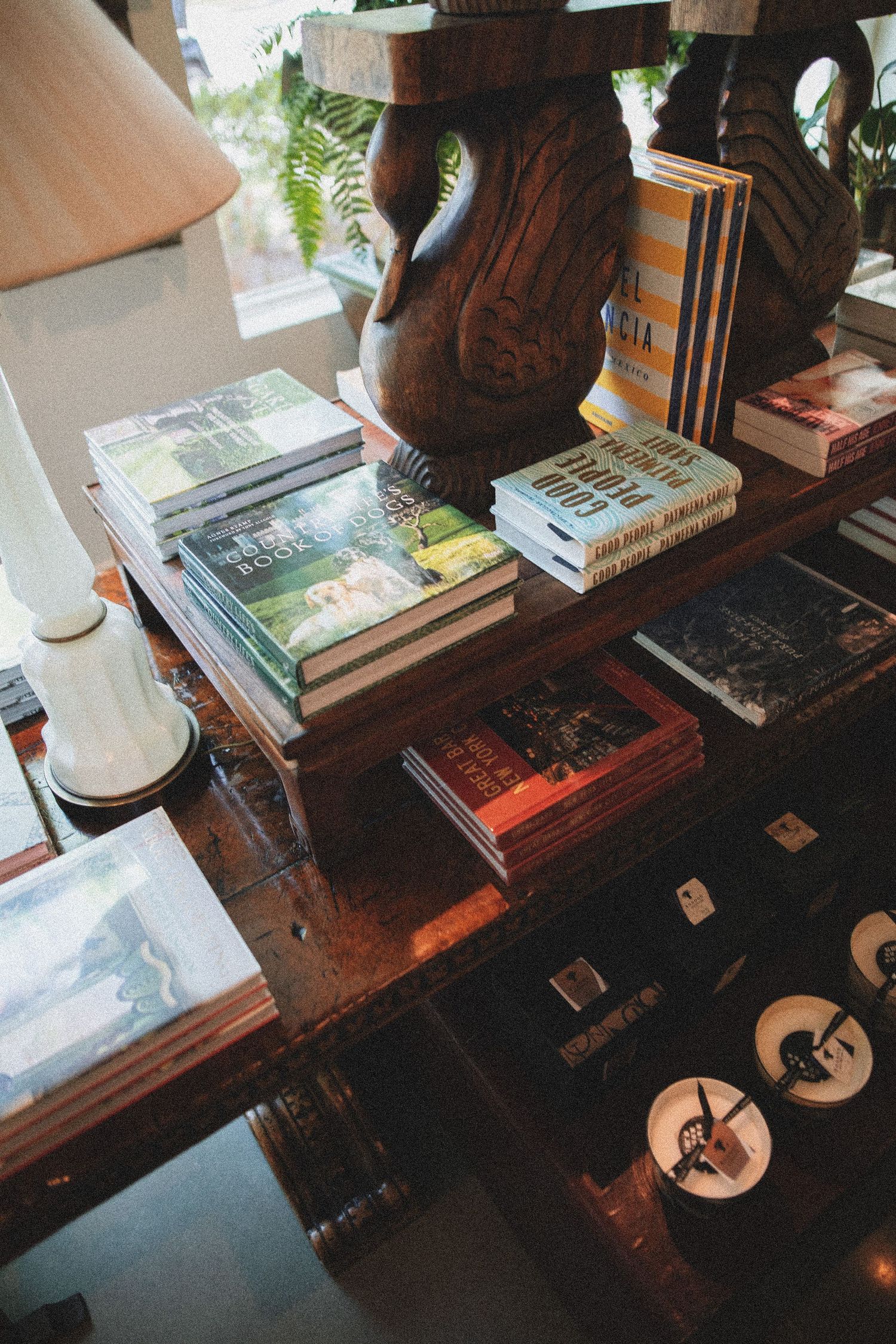 Wooden bookshelf displaying stacked books and decorative carved statue in a cozy bookstore setting.
