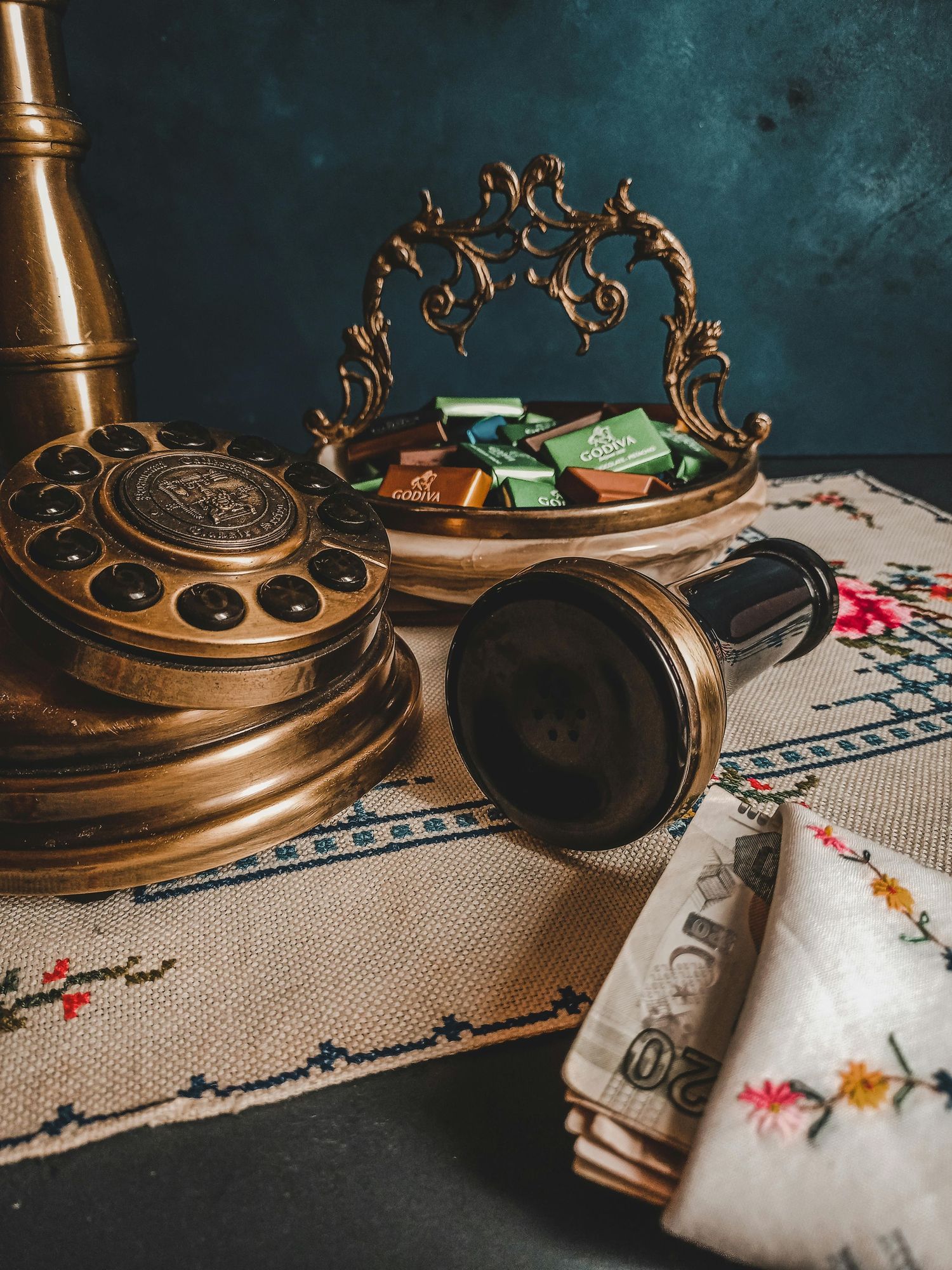 Antique brass decor items and embroidered linens arranged on textured surface.