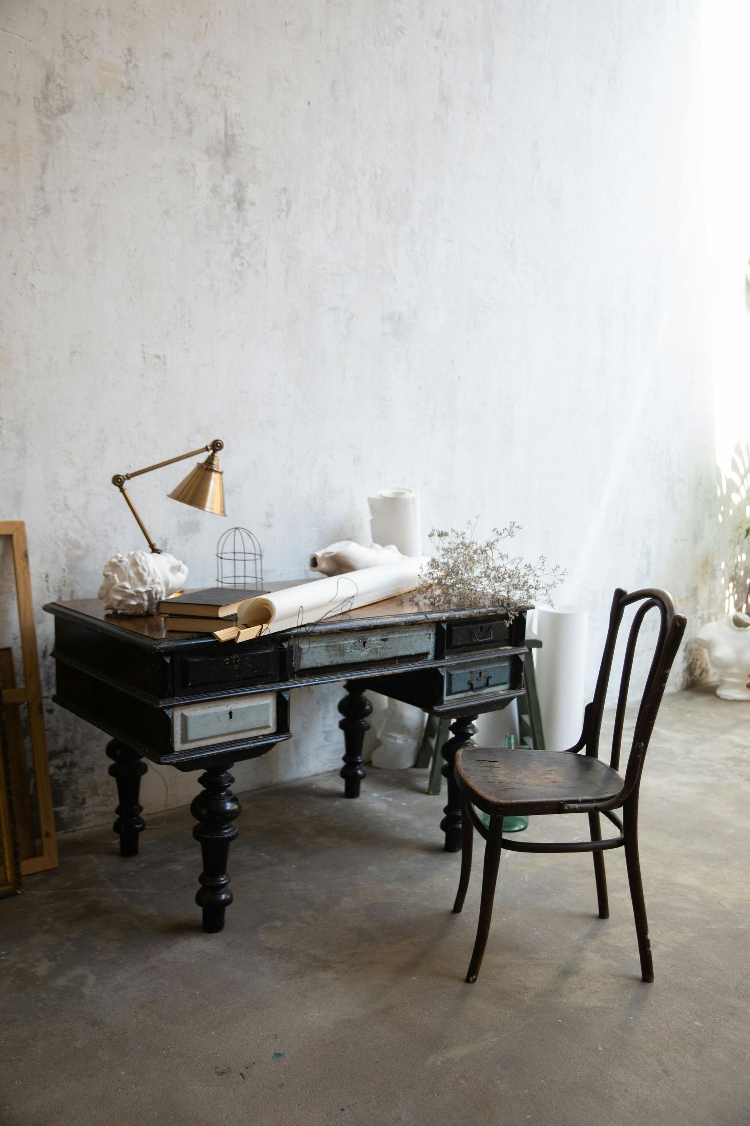 Minimalist room with black antique desk, chair, and white walls.