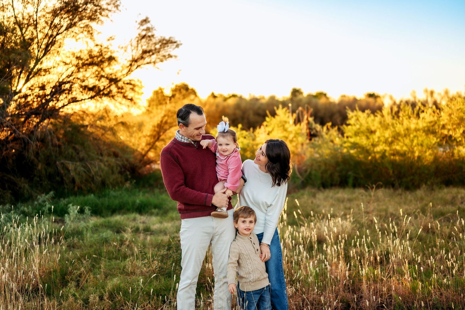 Family enjoying a golden sunset photoshoot in a grassy field during autumn.