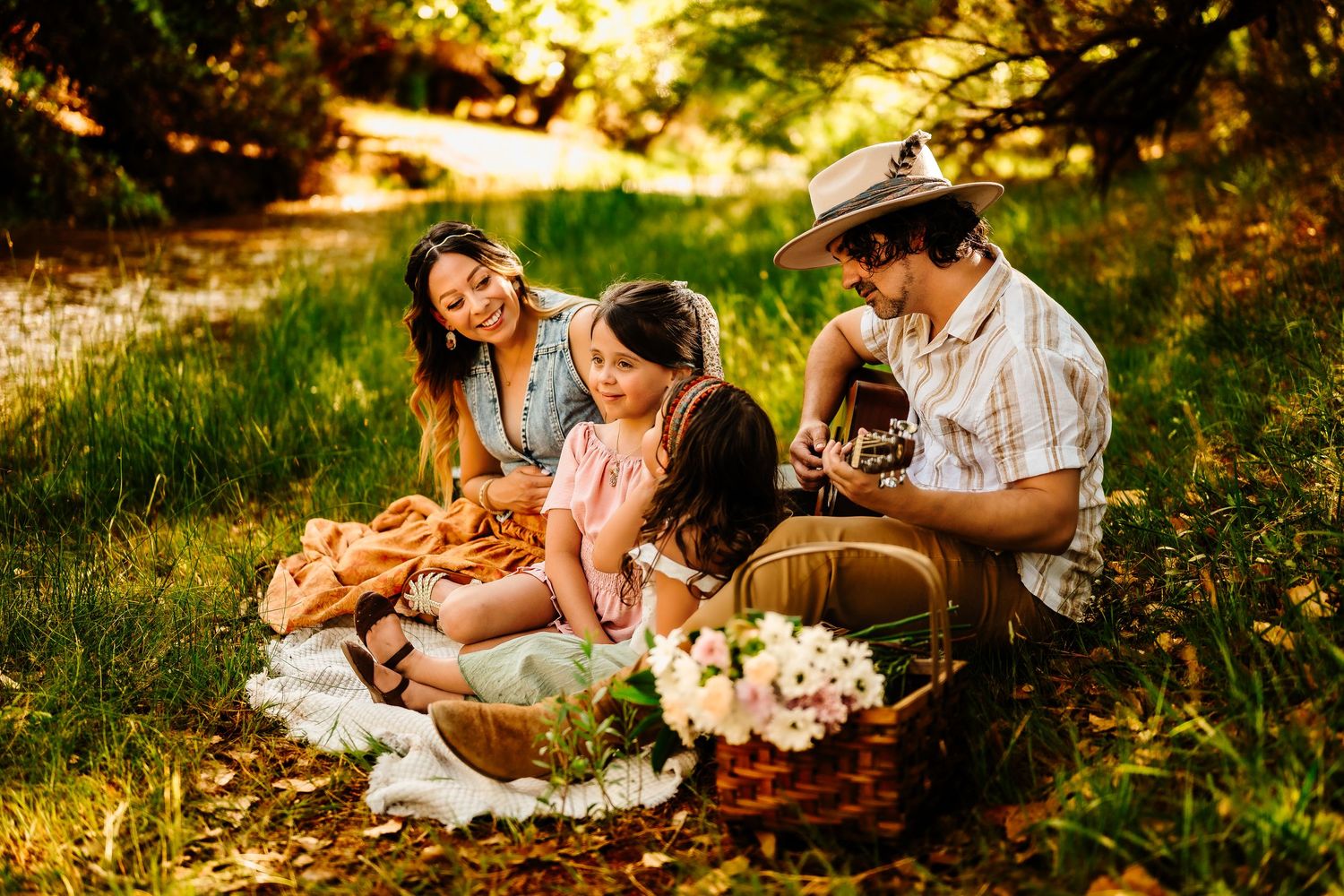 Family enjoying a picnic together on a grassy field during sunset.