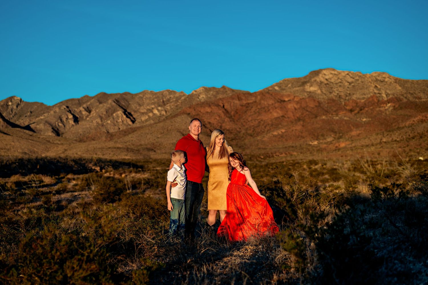 Family silhouettes against dramatic mountain backdrop at sunset.