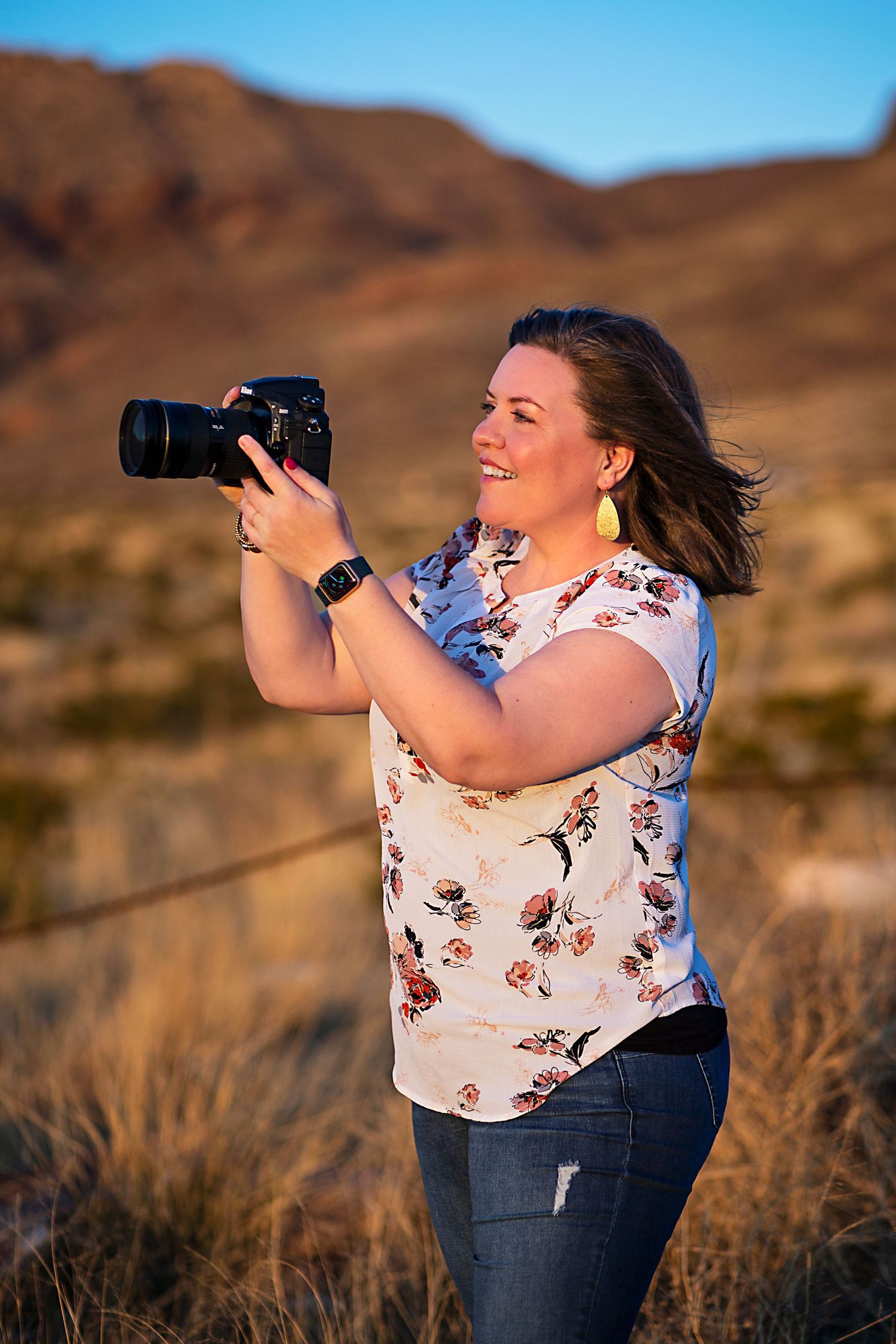 A photographer captures images in a desert landscape during golden hour.