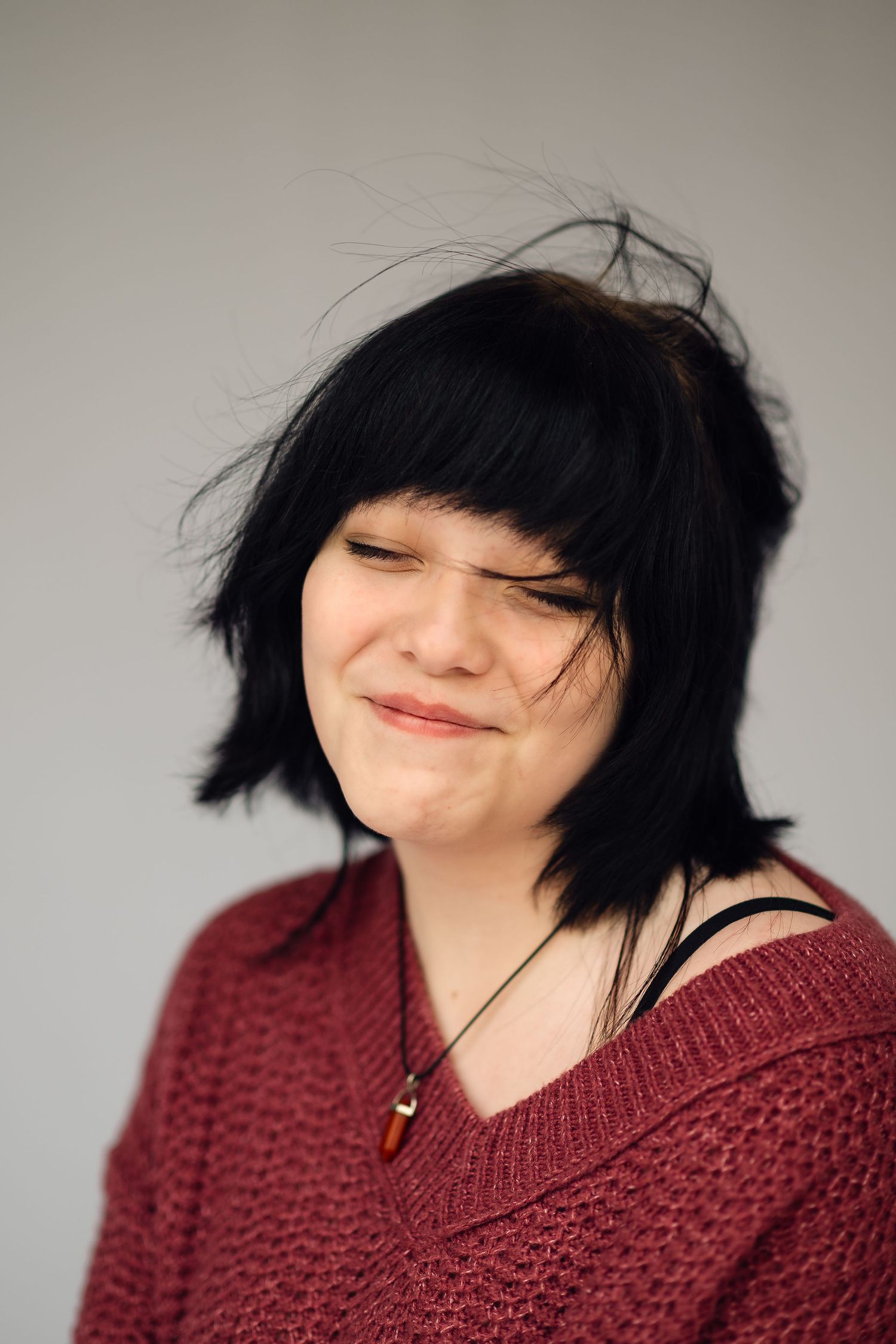 Person wearing burgundy sweater smiling with black hair against gray background in sequential photos.