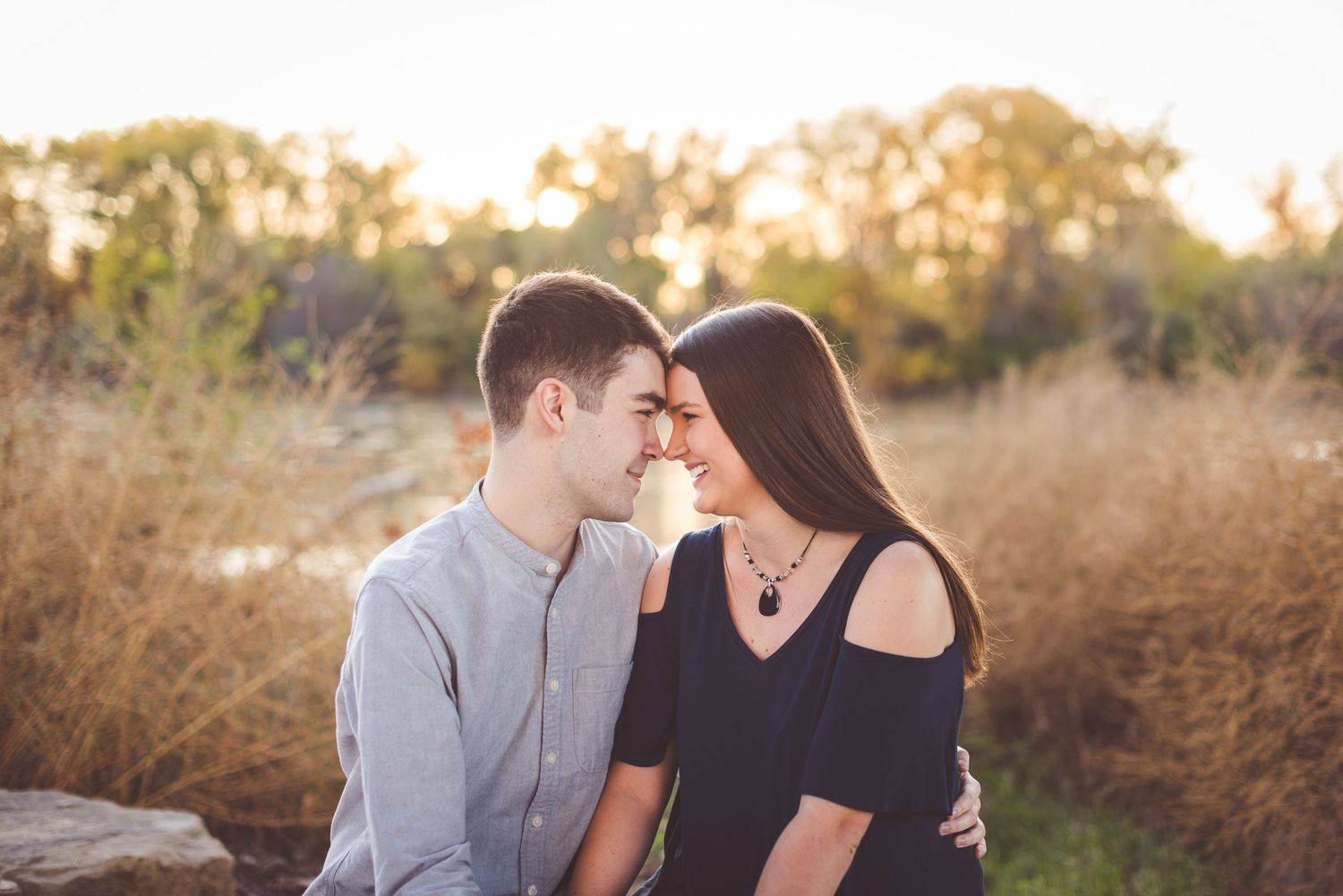 Romantic couple photoshoot during golden hour in a natural outdoor setting.