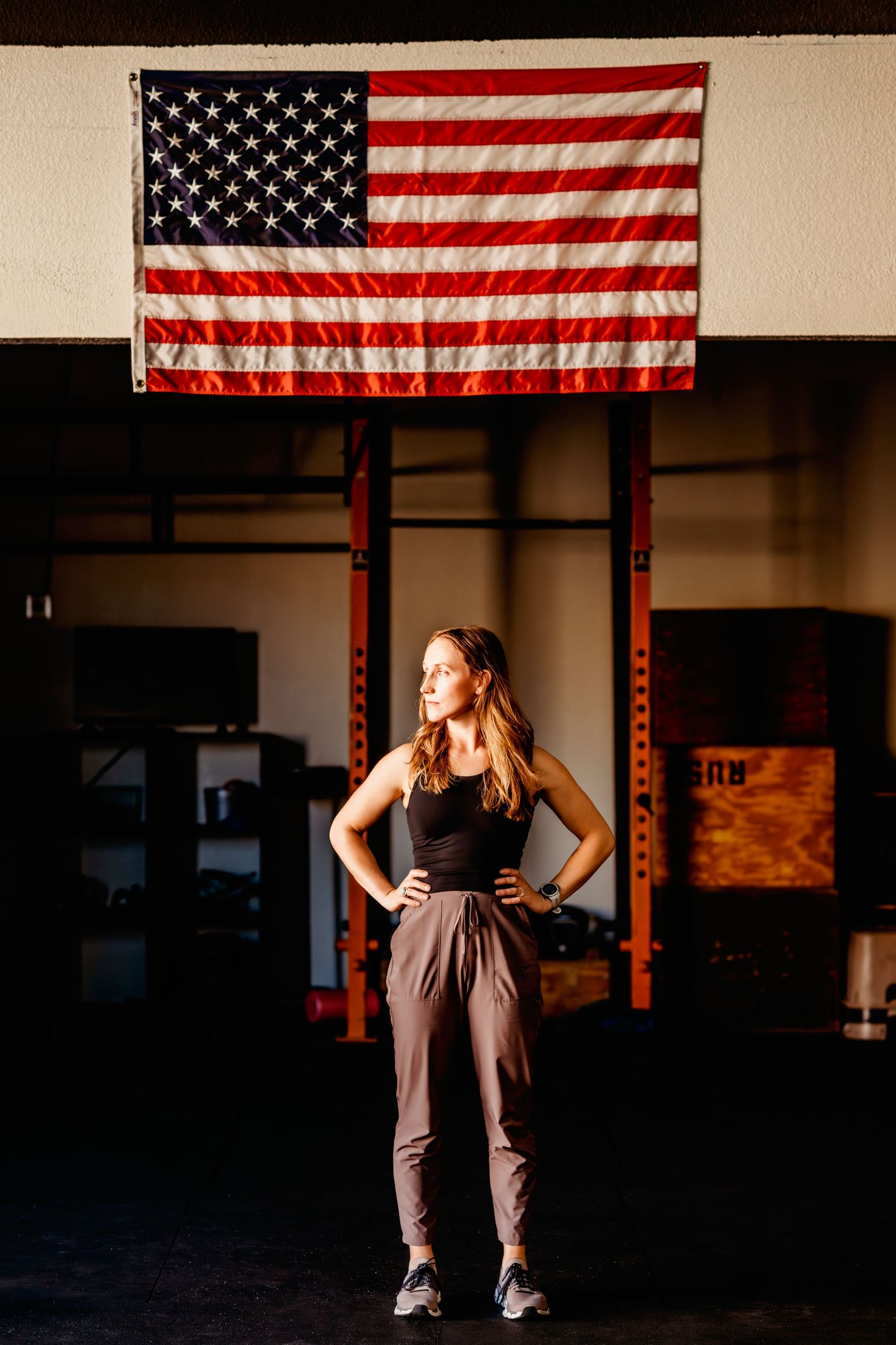 Silhouette poses against American flags in a dark indoor gym setting.