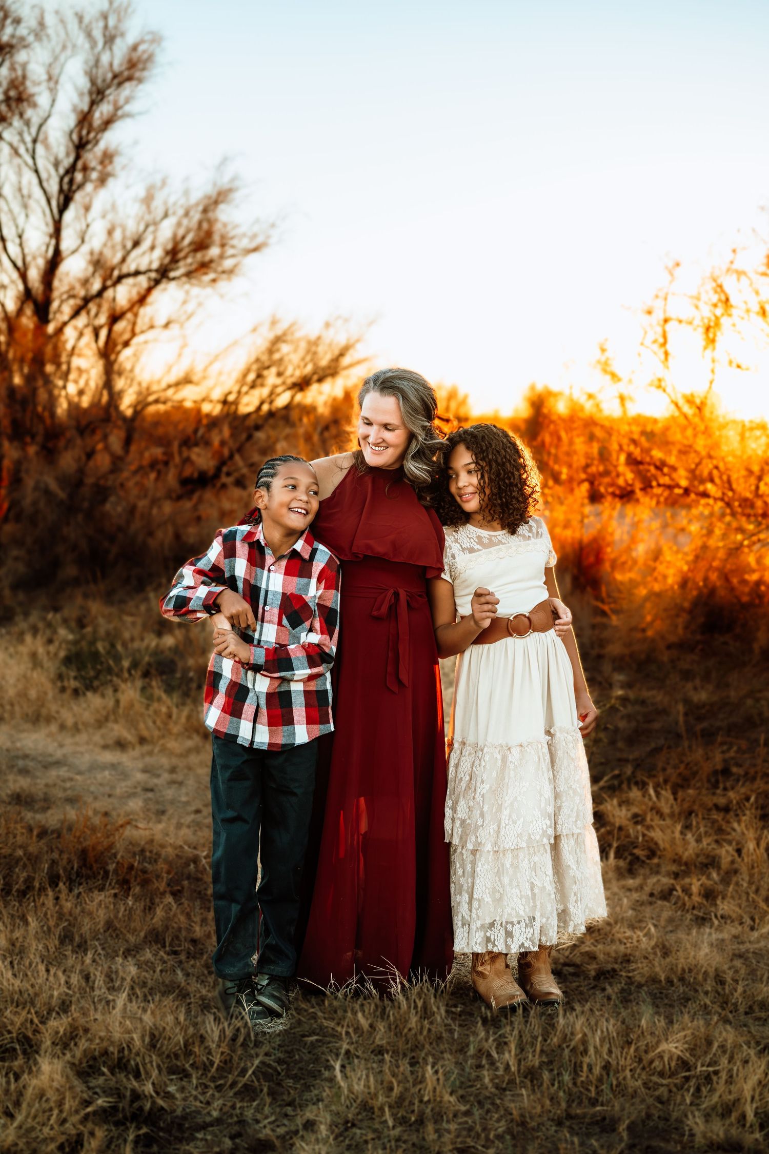 Family portrait in casual attire during golden hour against desert brush.