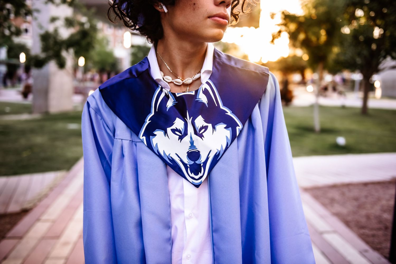 A person wearing a light blue button-up shirt poses in a series of outdoor photos at sunset.