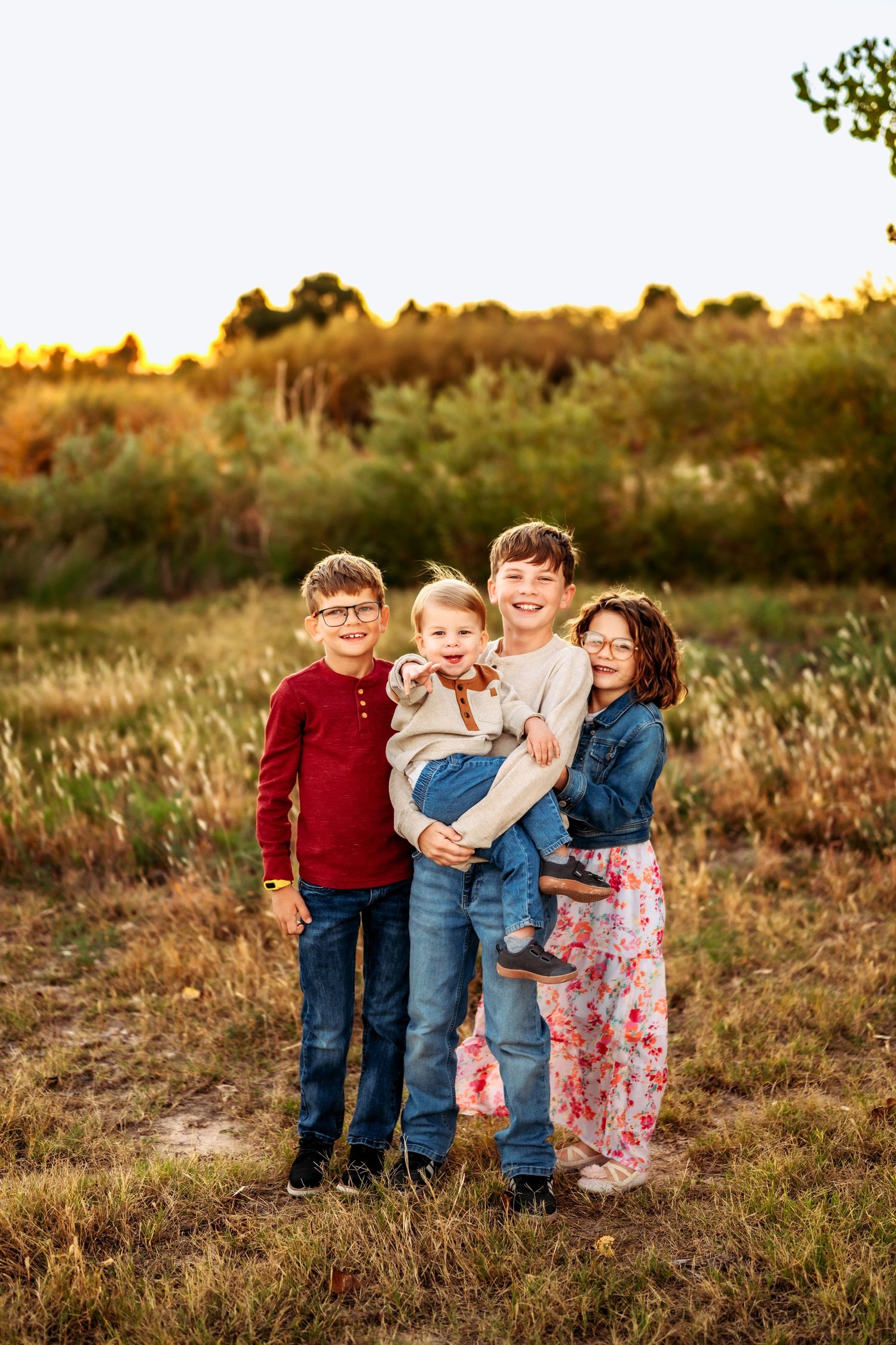 Group of children pose together in field during sunset.
