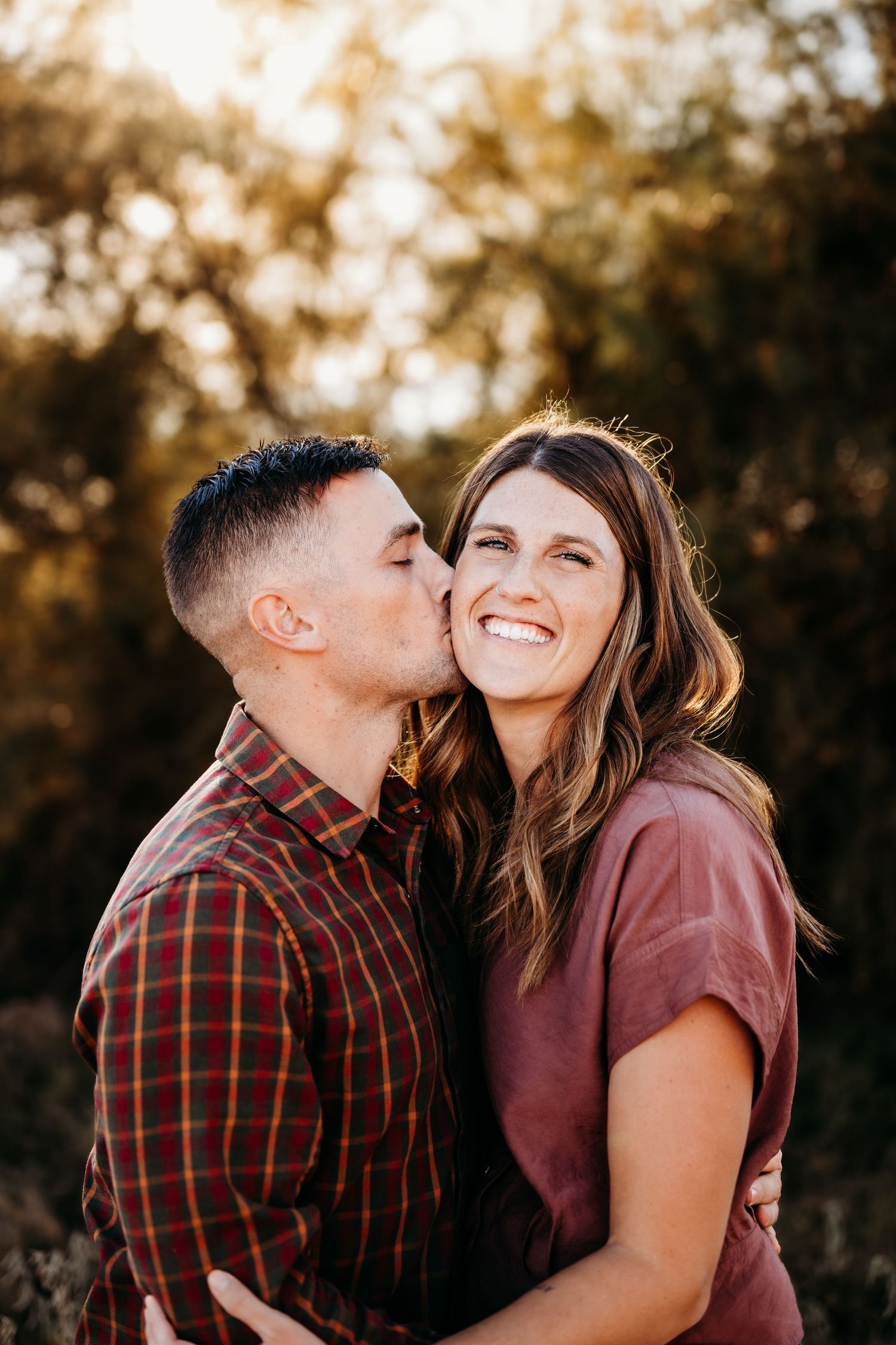 Romantic couple sharing tender moment during golden sunset in nature setting.