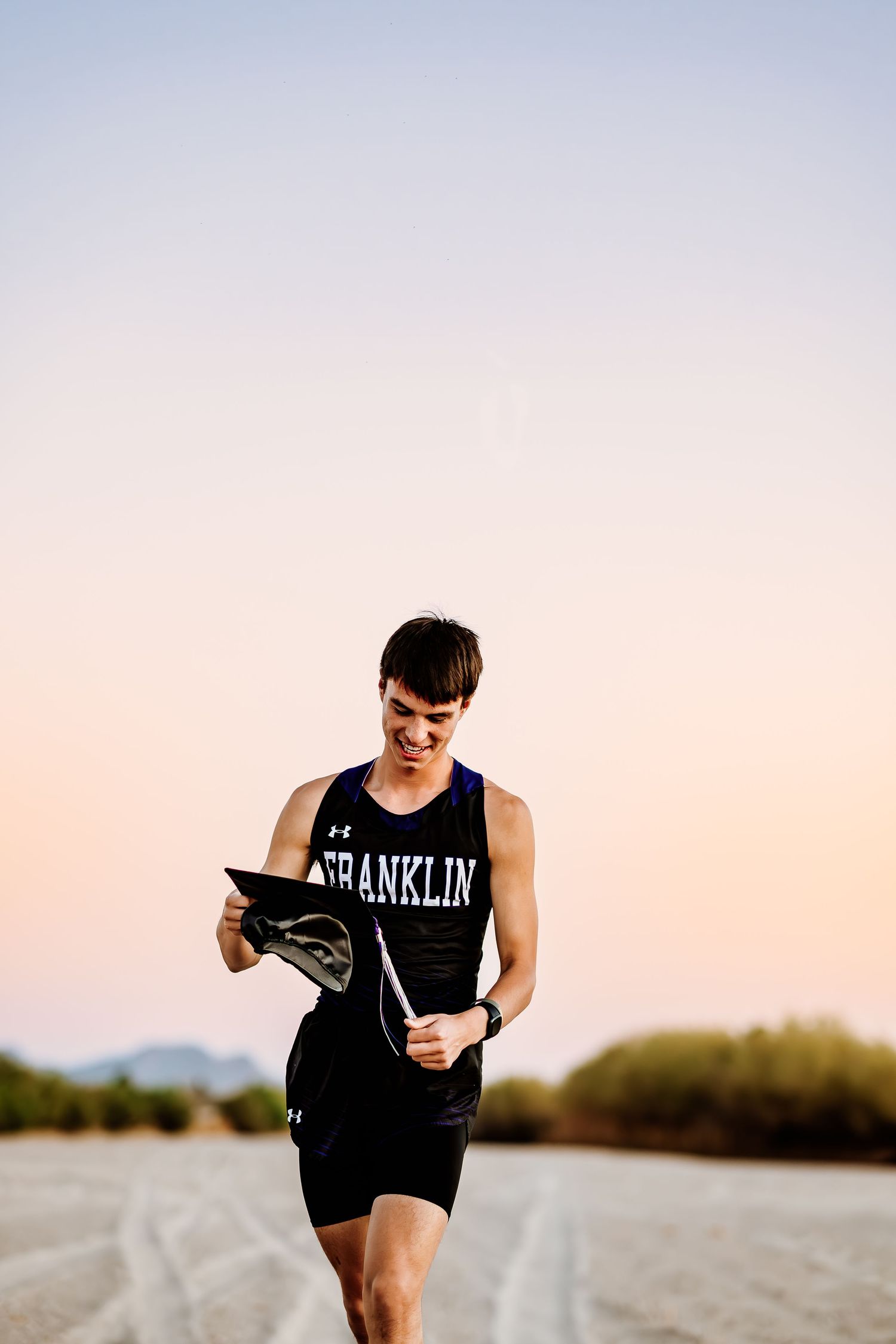 Athletic figure running at sunset wearing a Franklin tank top against a mountain backdrop.