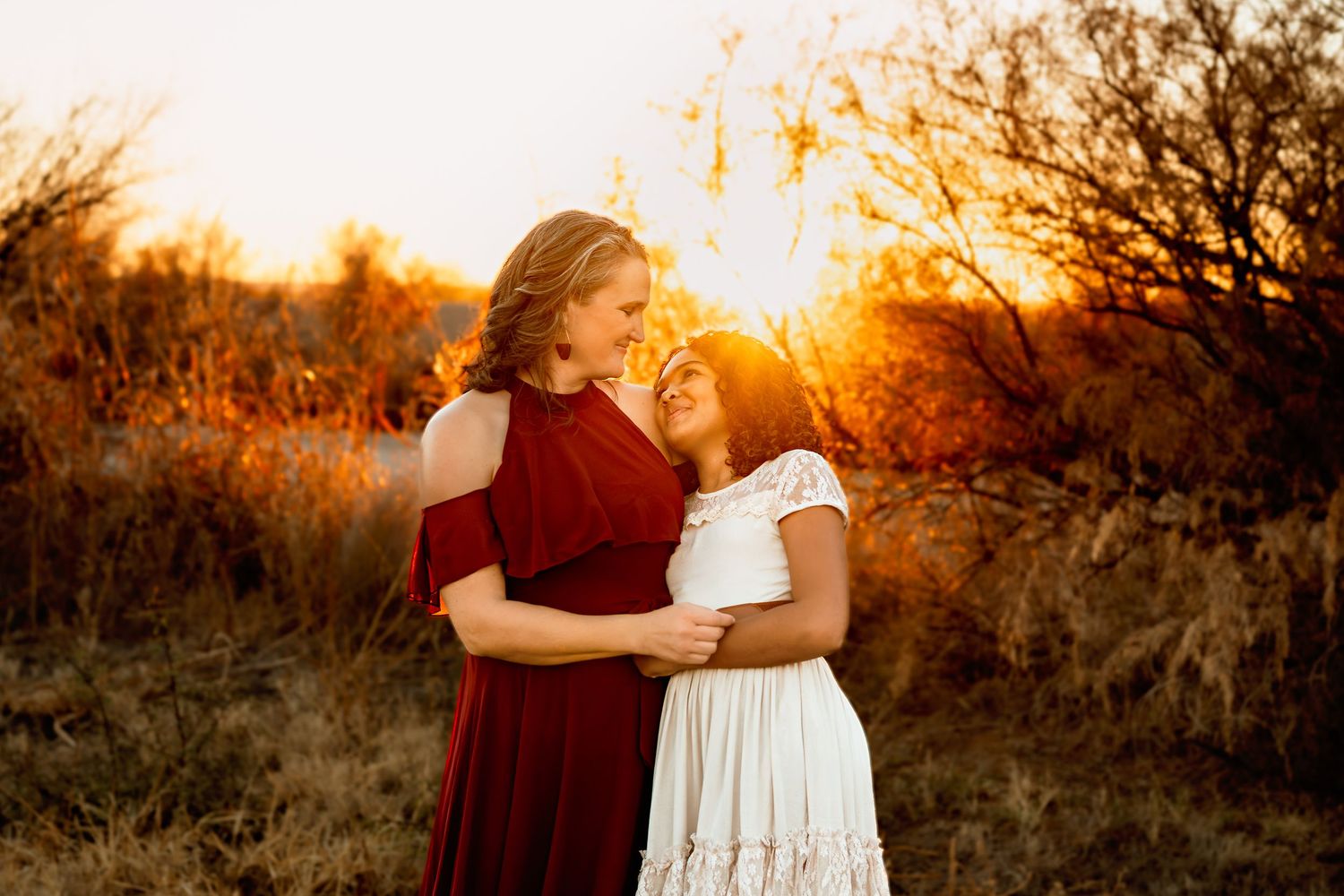 Two people embrace in a warm sunset glow amidst natural desert scenery.