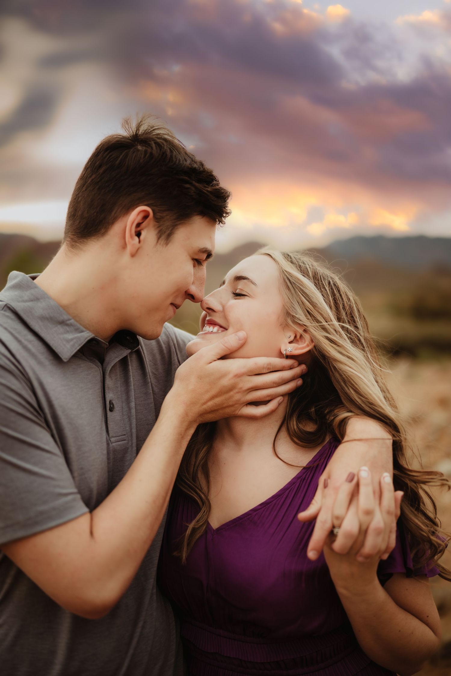Intimate couple portrait session during dramatic sunset with mountain backdrop.