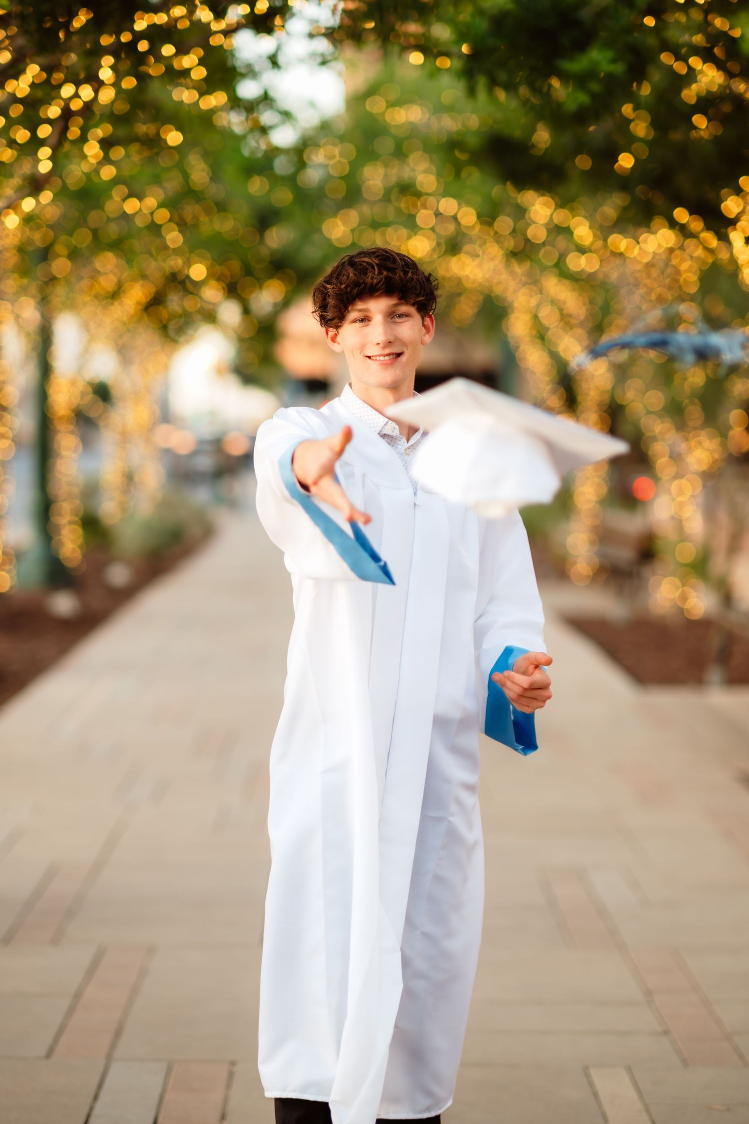 Person in white shirt performing playful poses on a sunlit outdoor walkway.