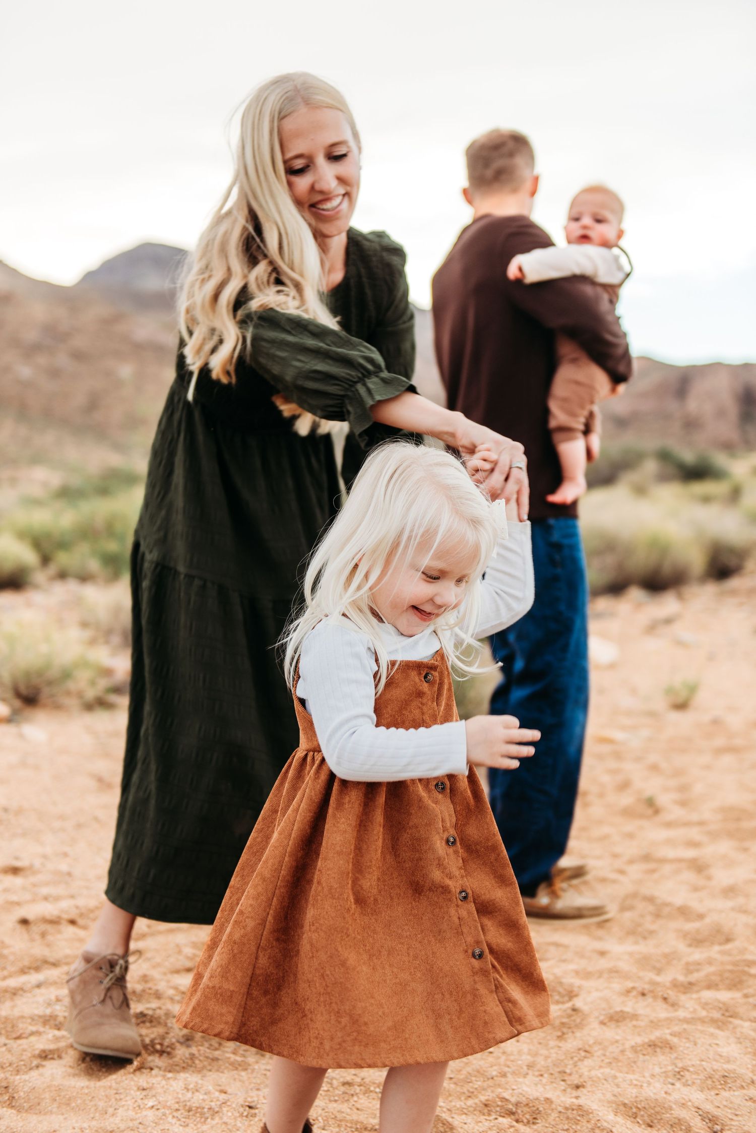 Family in desert landscape with young child in brown dress in foreground.