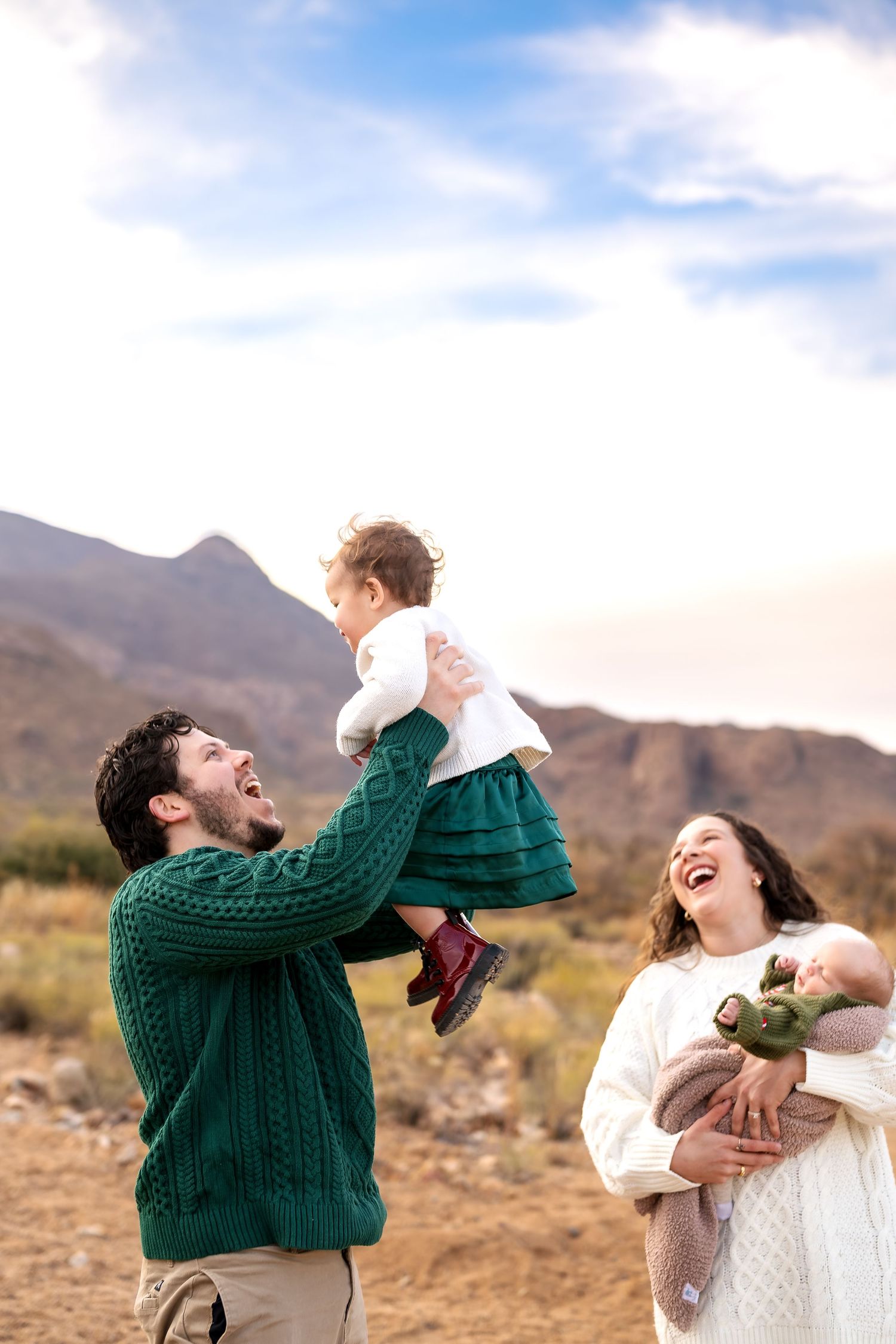 Joyful family interaction captured in desert setting with mountains in background.