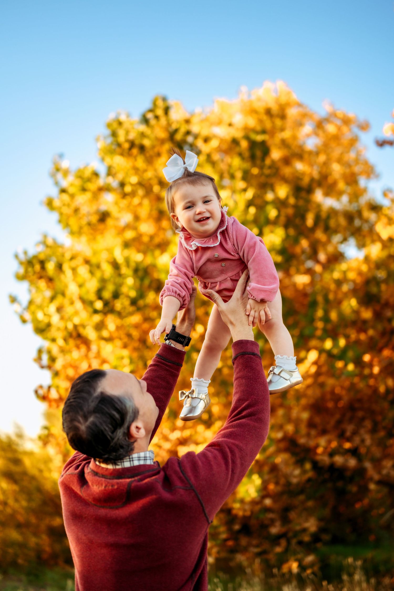 Playful moments captured in front of vibrant fall foliage at sunset.