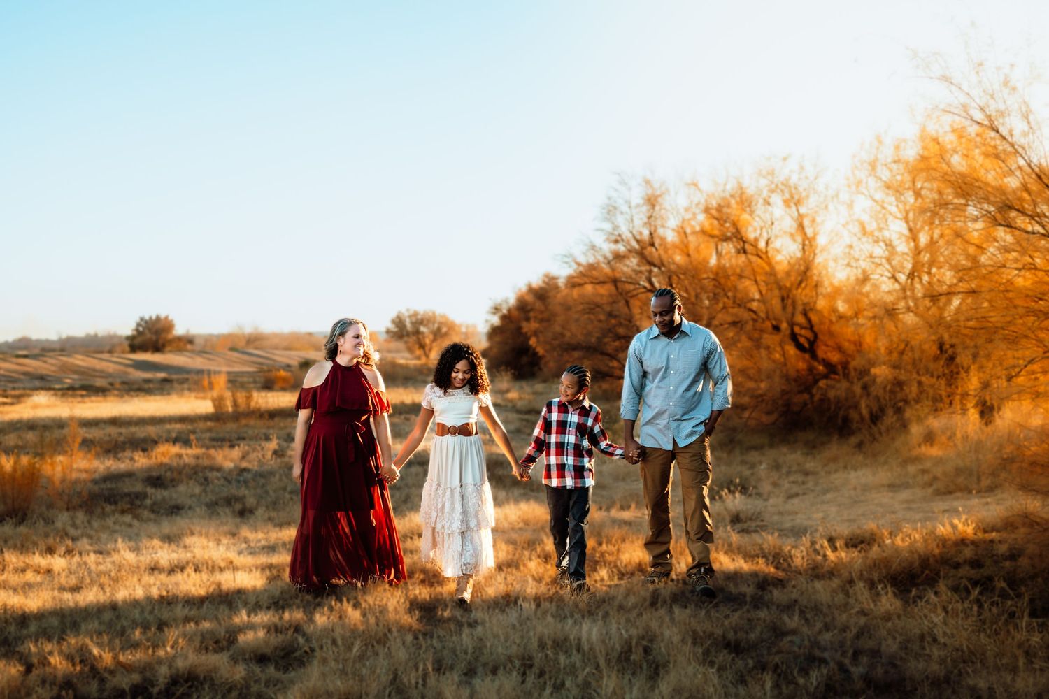 Family walks together through a field at golden hour.