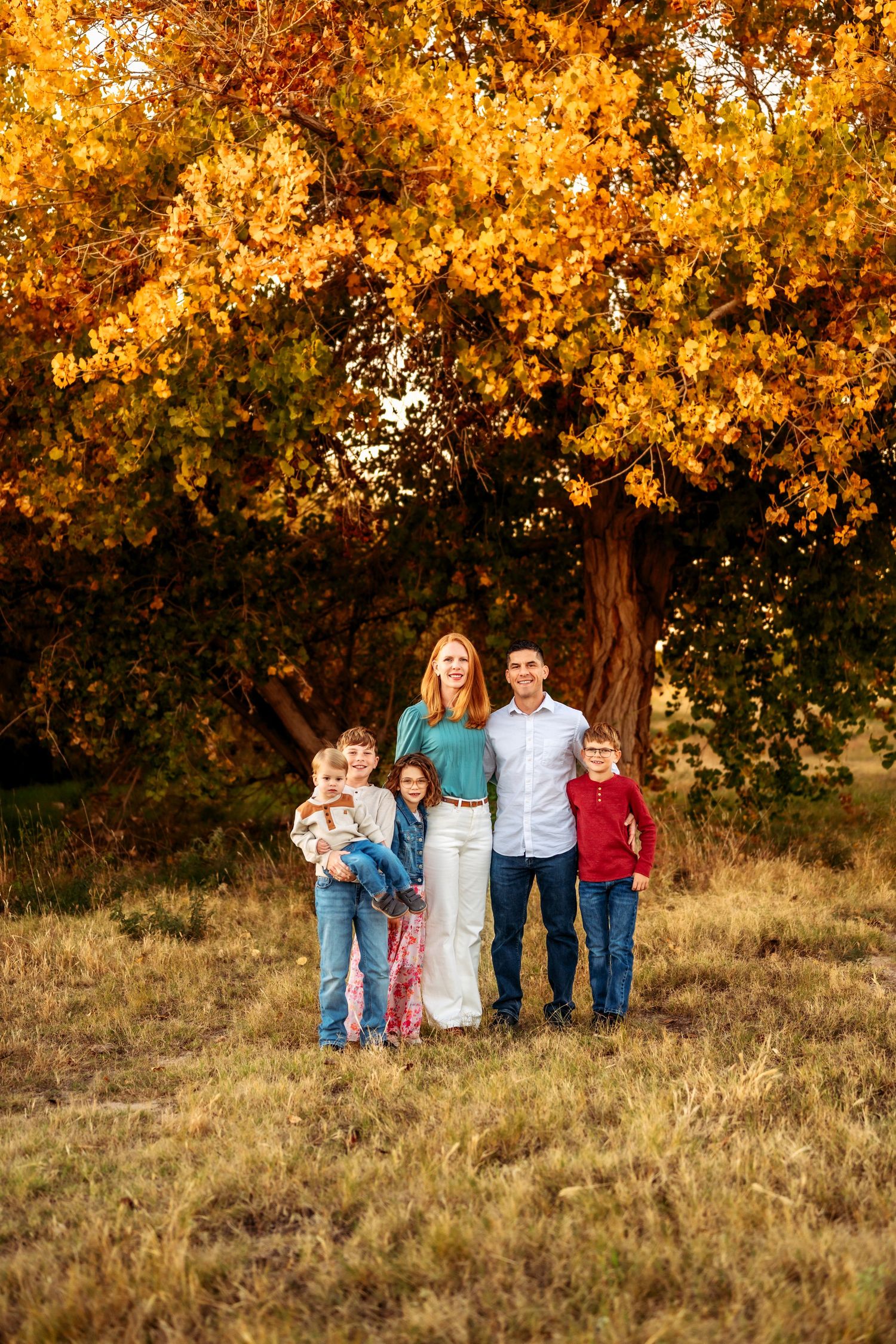 Family gathering under golden autumn trees in a natural outdoor setting.