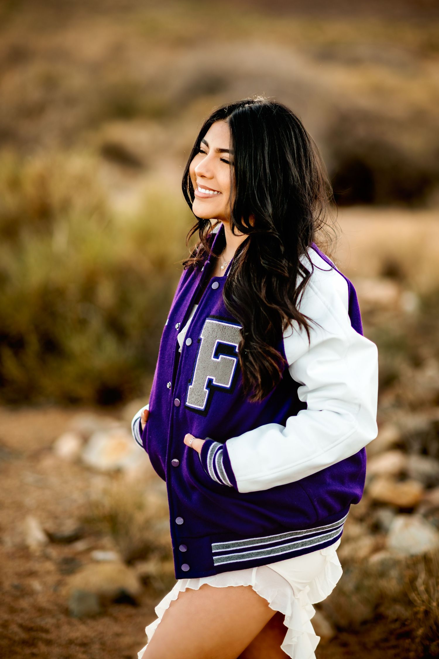 Athletic letterman jacket photo shoot in desert setting with natural lighting.
