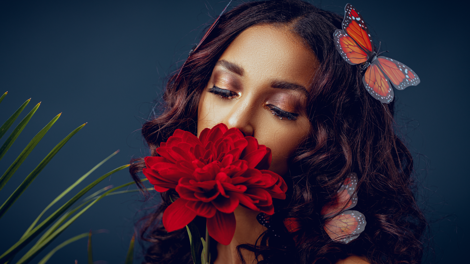 Artistic beauty portrait with red flowers and gold crown against dark background.