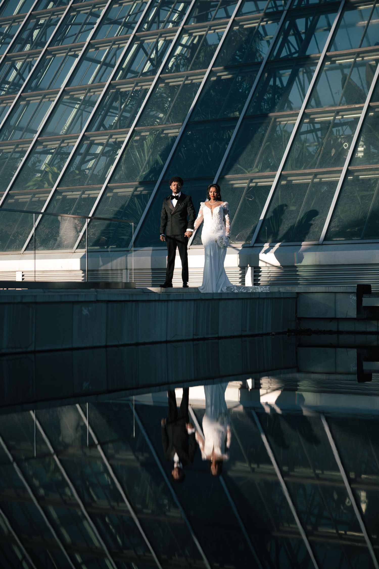 Modern glass architecture creates geometric reflections with silhouettes against bright light.