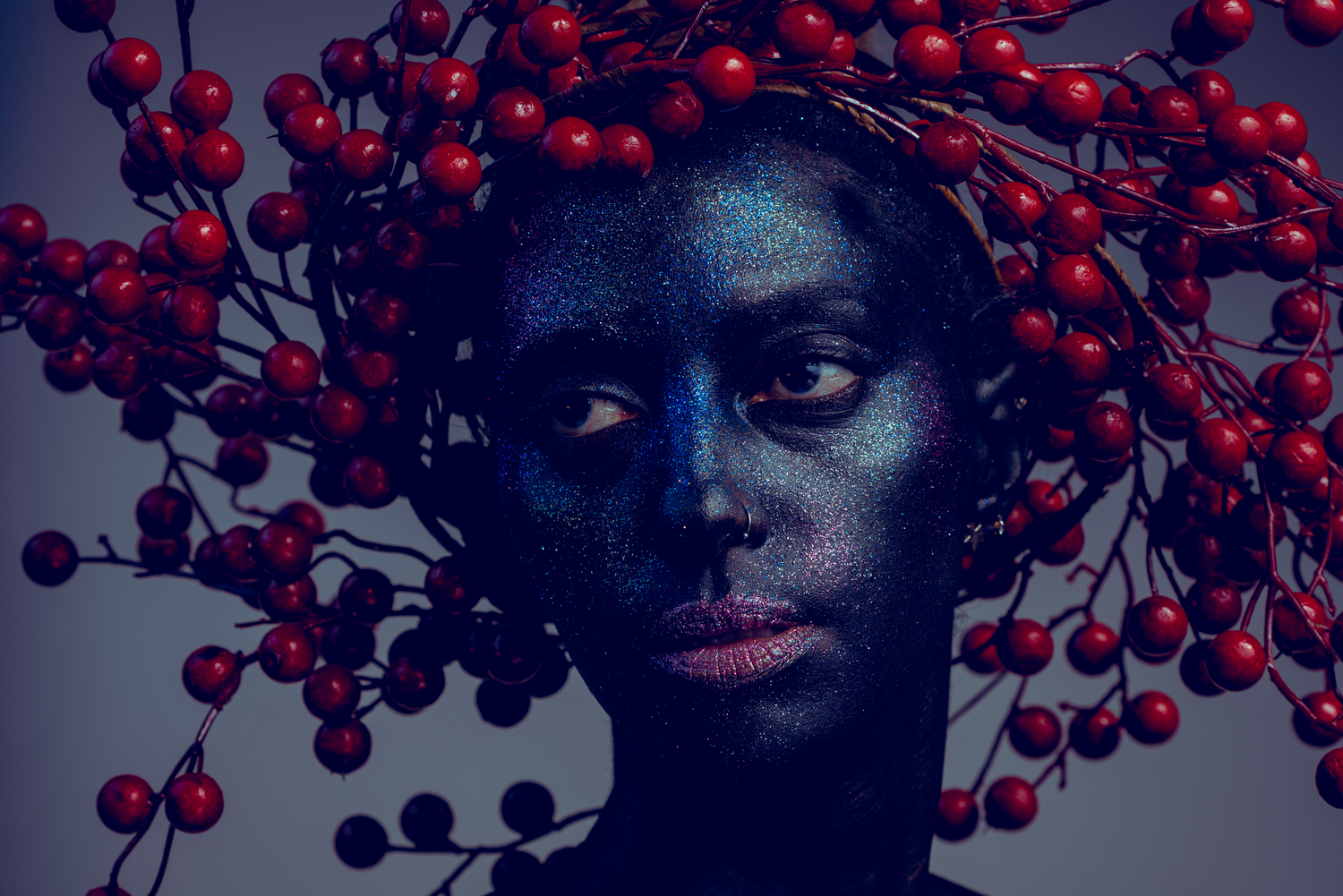 Dark artistic portrait with red winter berries creating dramatic contrast.