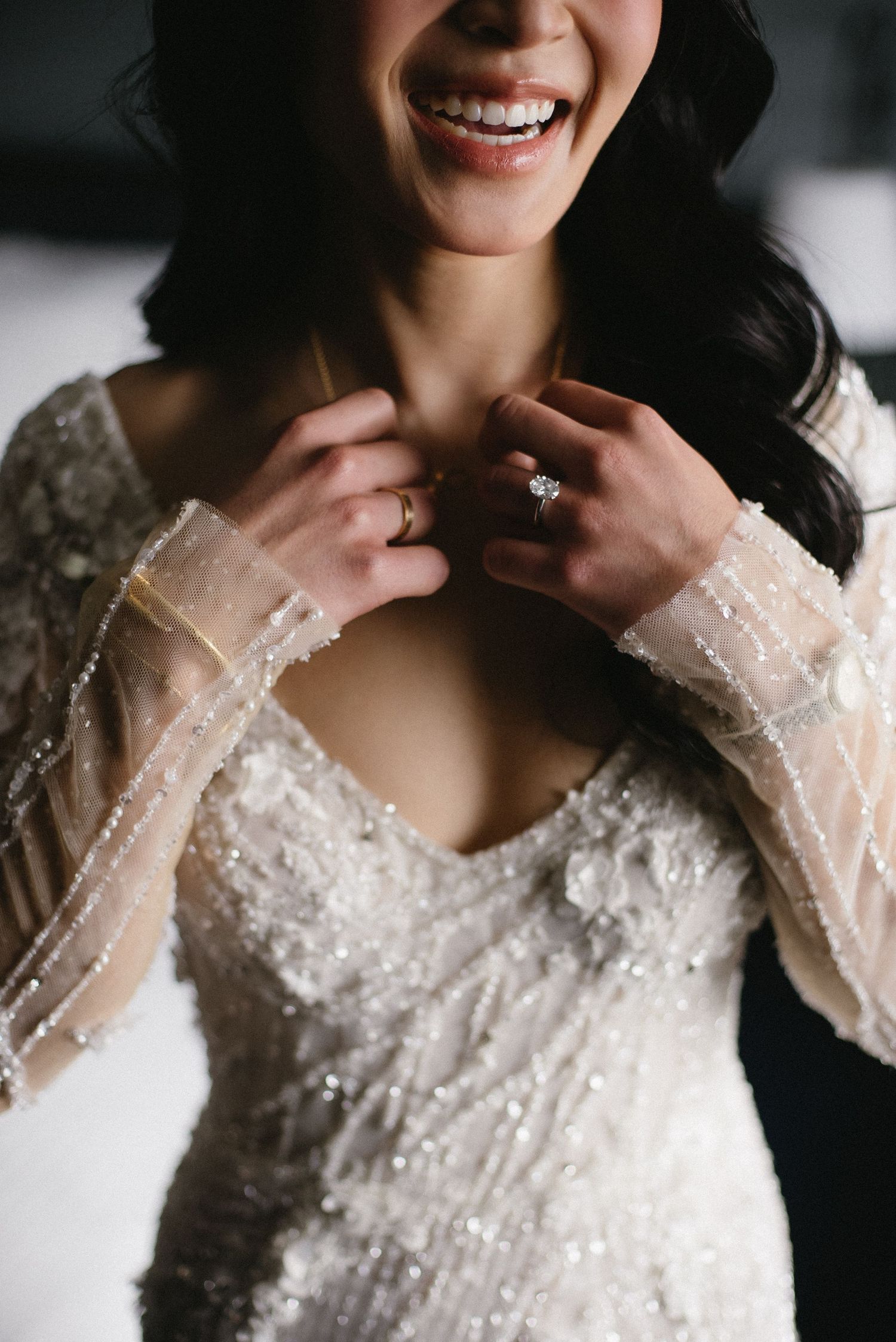 Close-up view of a beaded white wedding dress with intricate pearl and crystal details.