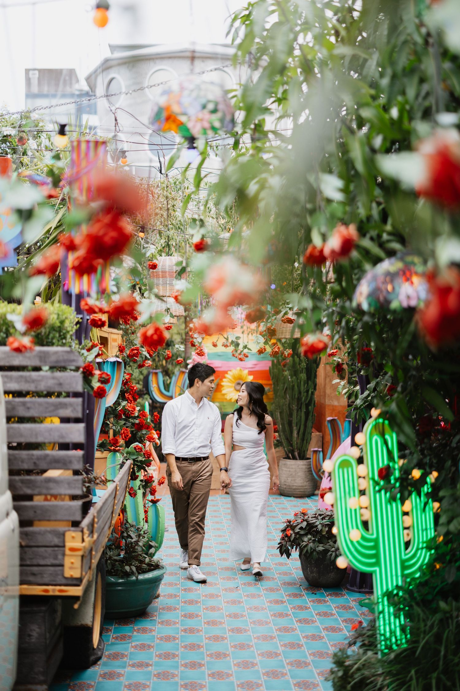 Garden wedding setting with red flowers and glowing green cactus neon sign.