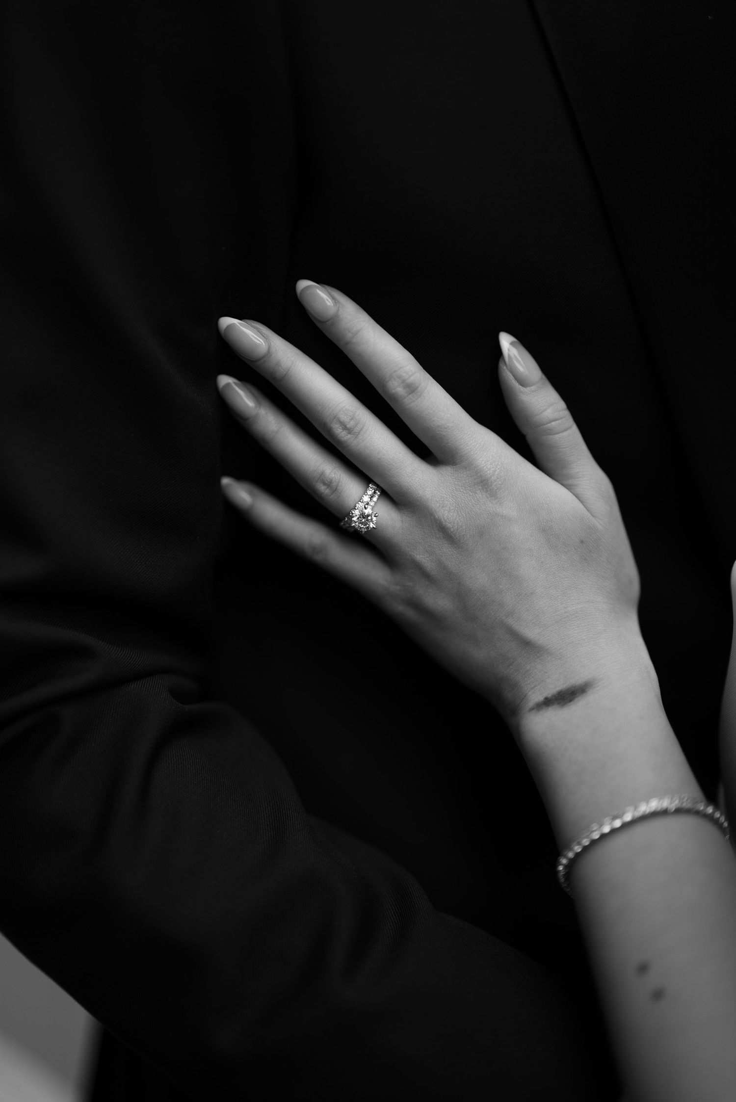 A series of black and white photographs showing a hand wearing an engagement ring and bracelet against a dark background.