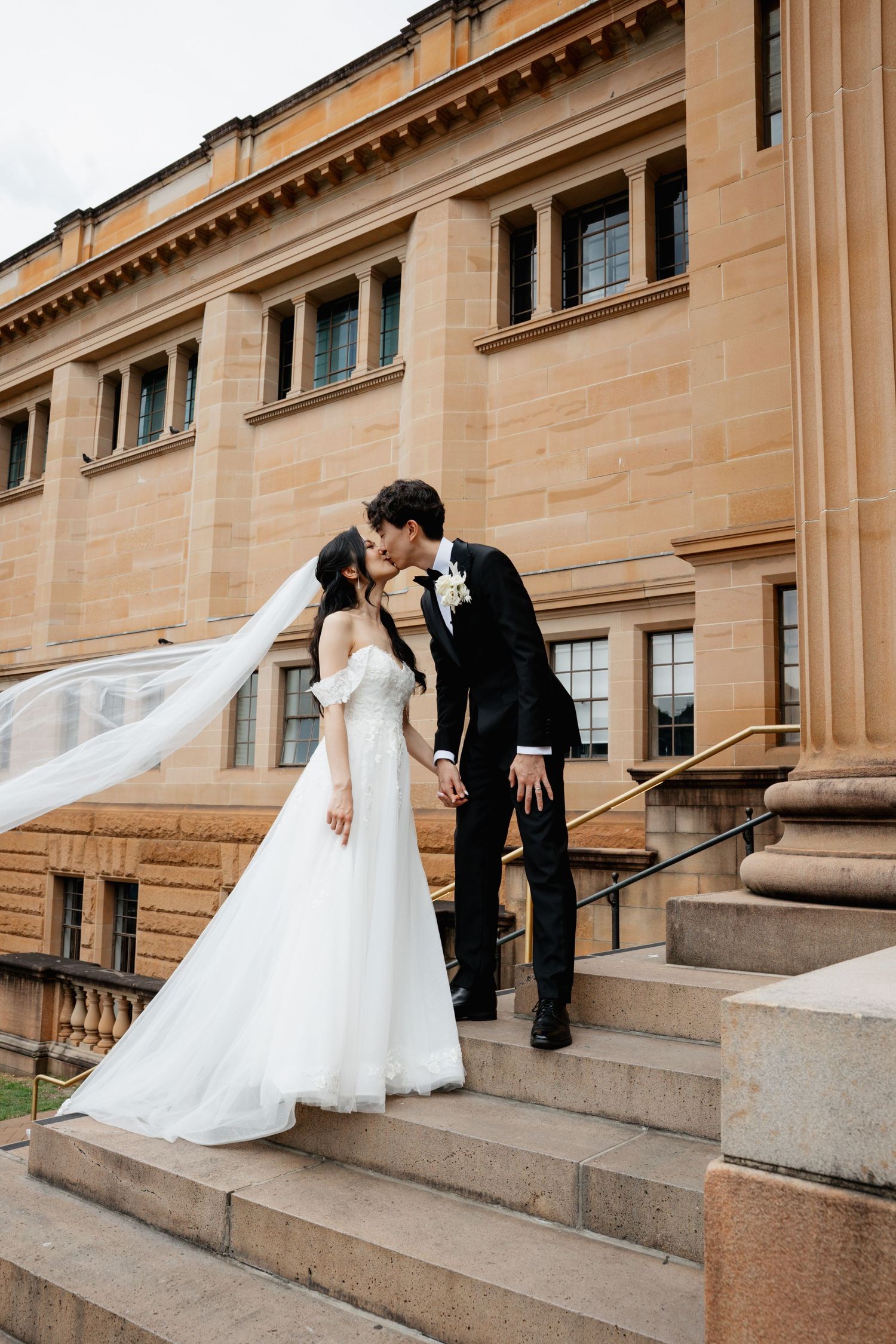 A romantic wedding photo sequence showing a couple sitting and leaning towards each other on stone steps of a grand building.