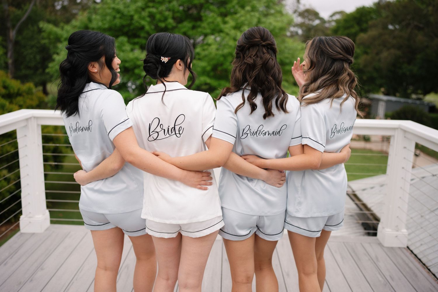 Group wearing matching white button-down shirts and gray shorts pose together on white deck railing.