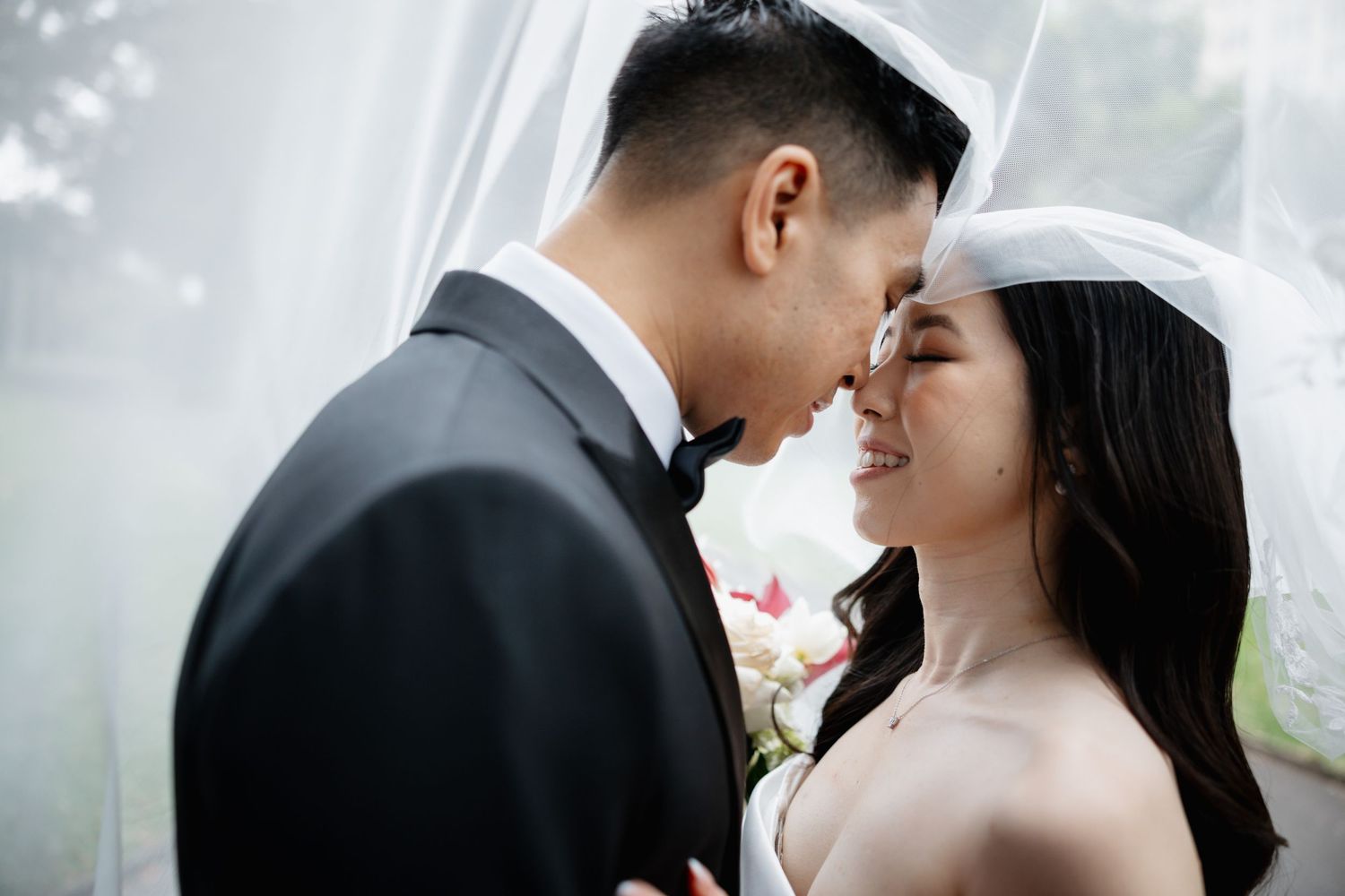 A couple shares a tender kiss during their wedding ceremony with a soft blurred background.