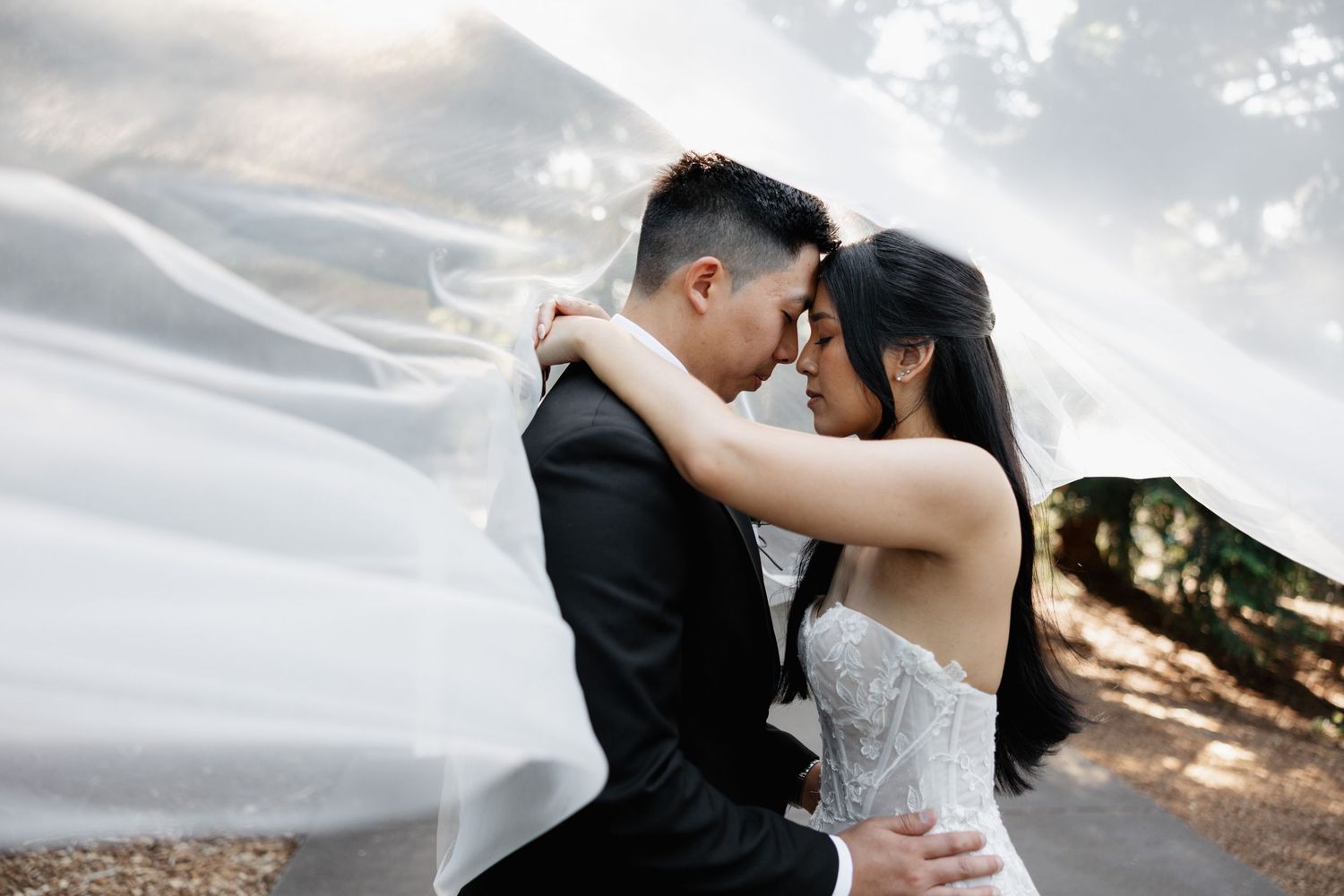 A romantic wedding photoshoot with flowing veil against a dramatic cloudy sky.