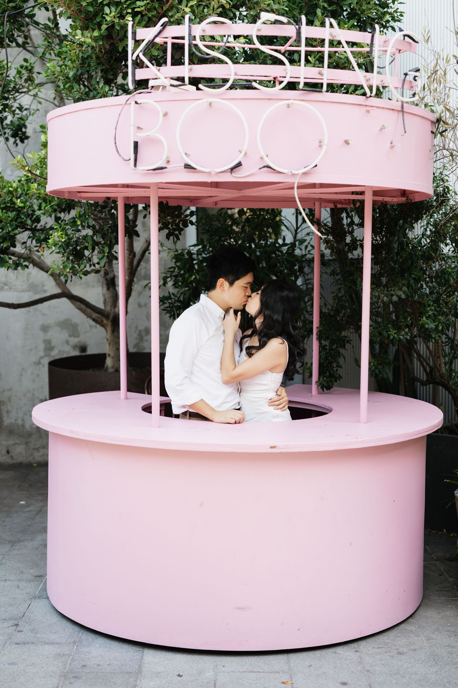 Wedding photos taken in front of a round pink booth or kiosk structure.