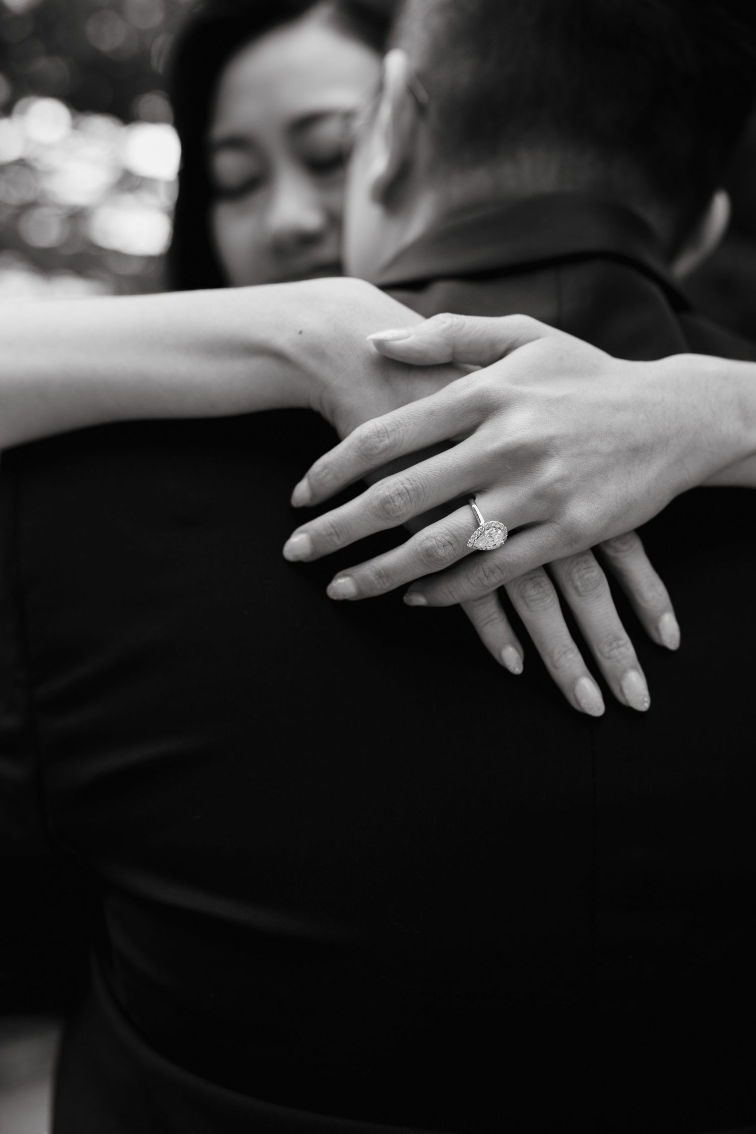 Close-up of hands with engagement ring in black and white.