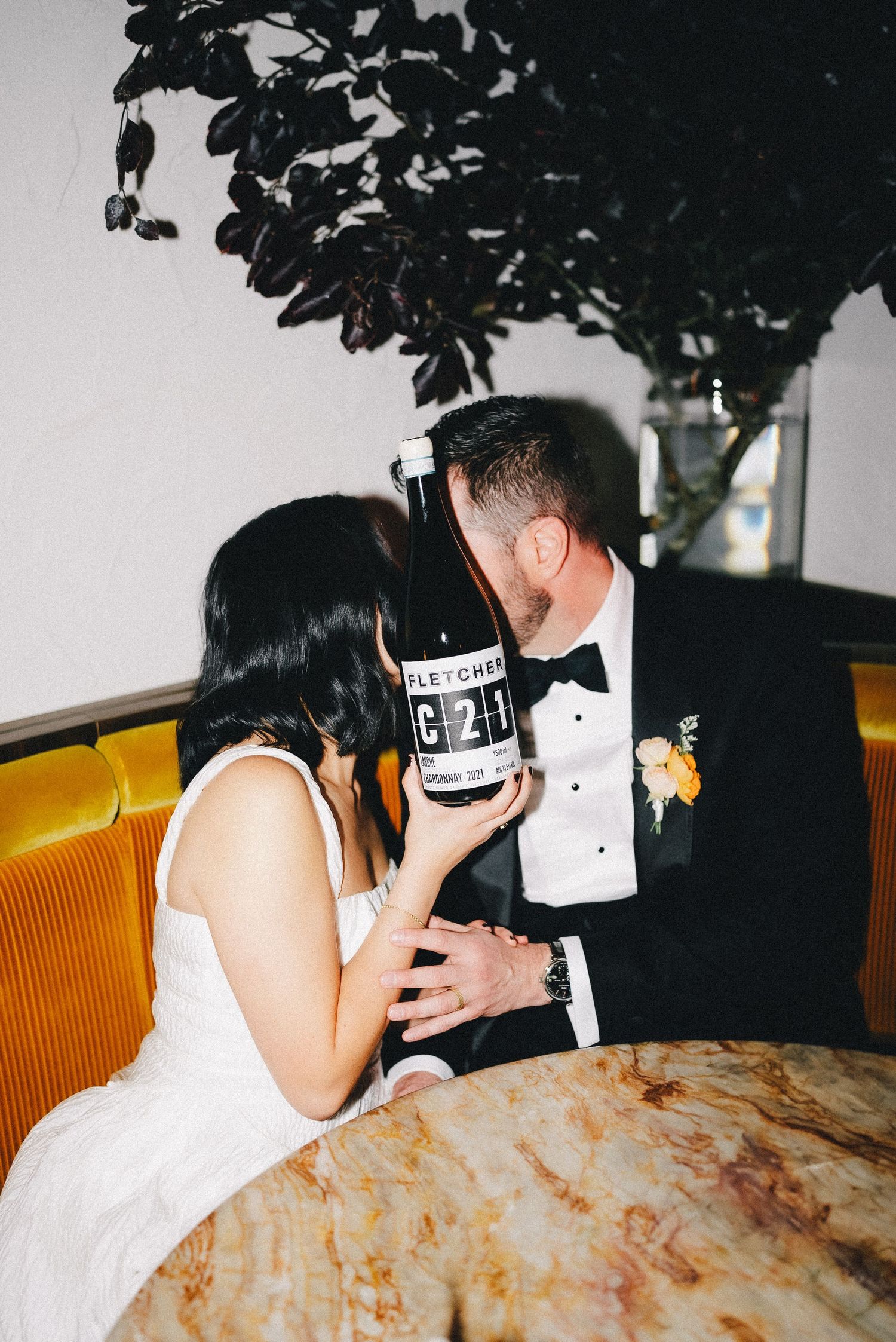 An intimate moment between a couple in formal attire at a dimly lit venue.