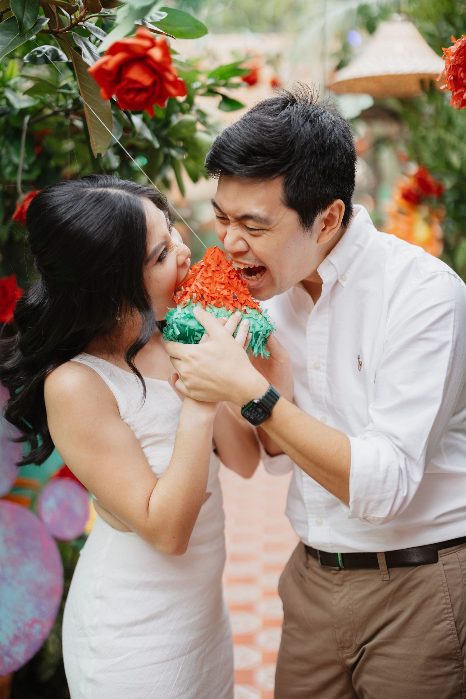 Romantic garden wedding photos with red flowers and greenery in background.