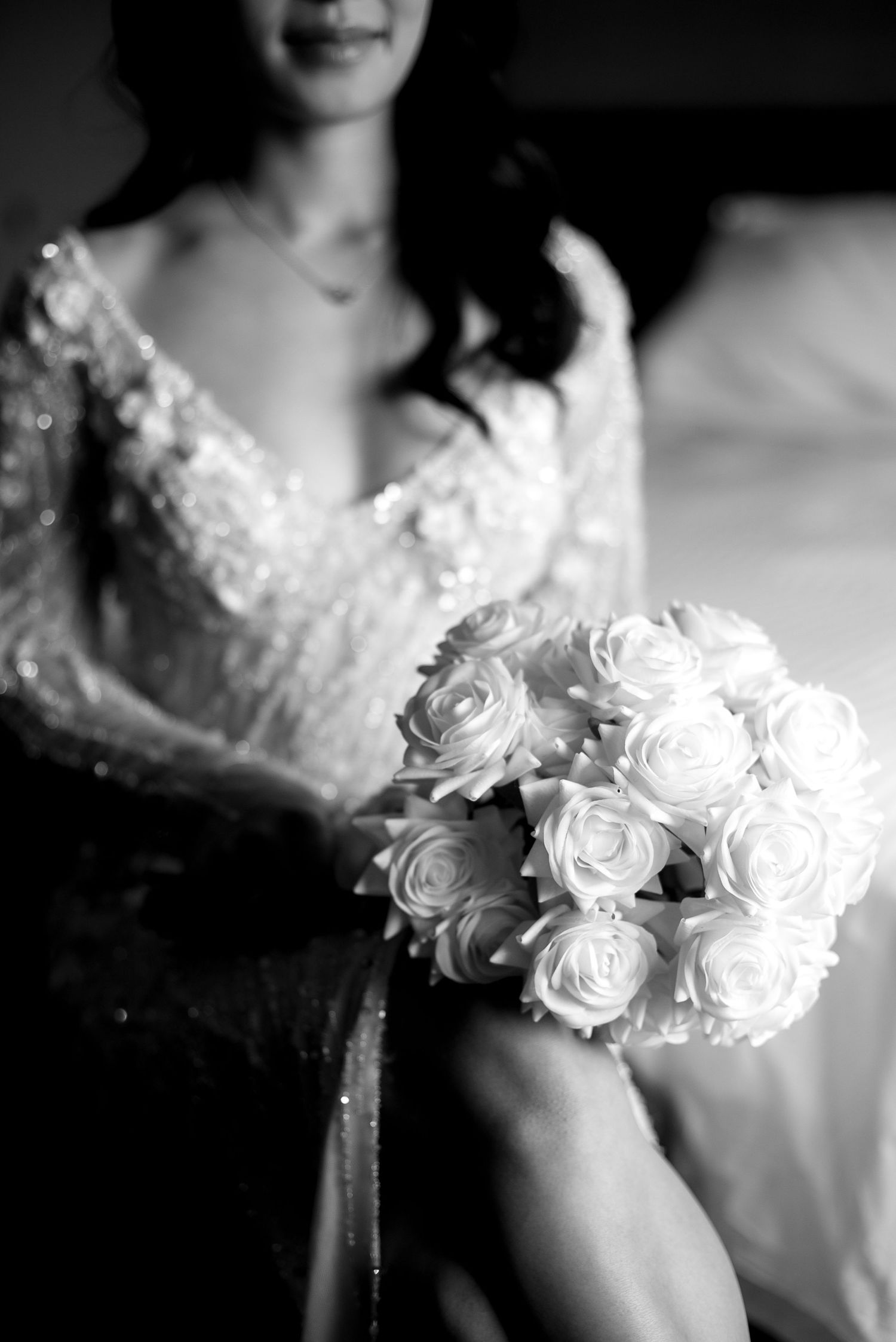 A series of black and white wedding photos showing delicate white roses and lace details on a bridal gown.