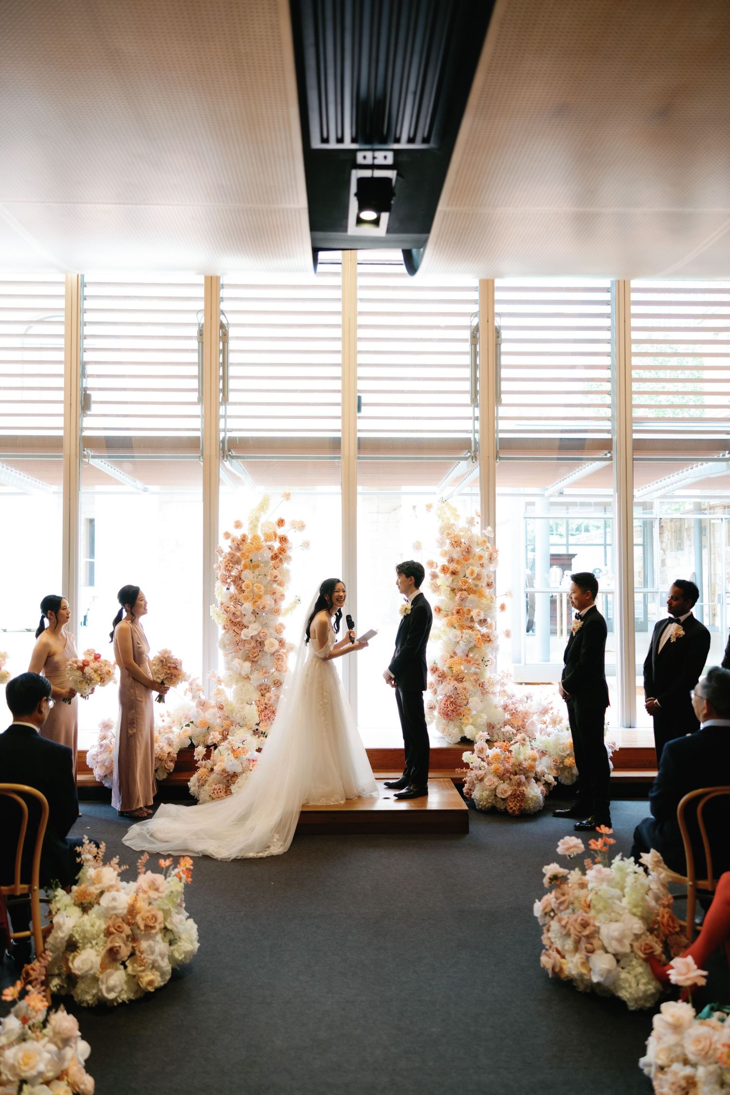 Wedding ceremony setup in modern venue with pink and white floral arrangements.