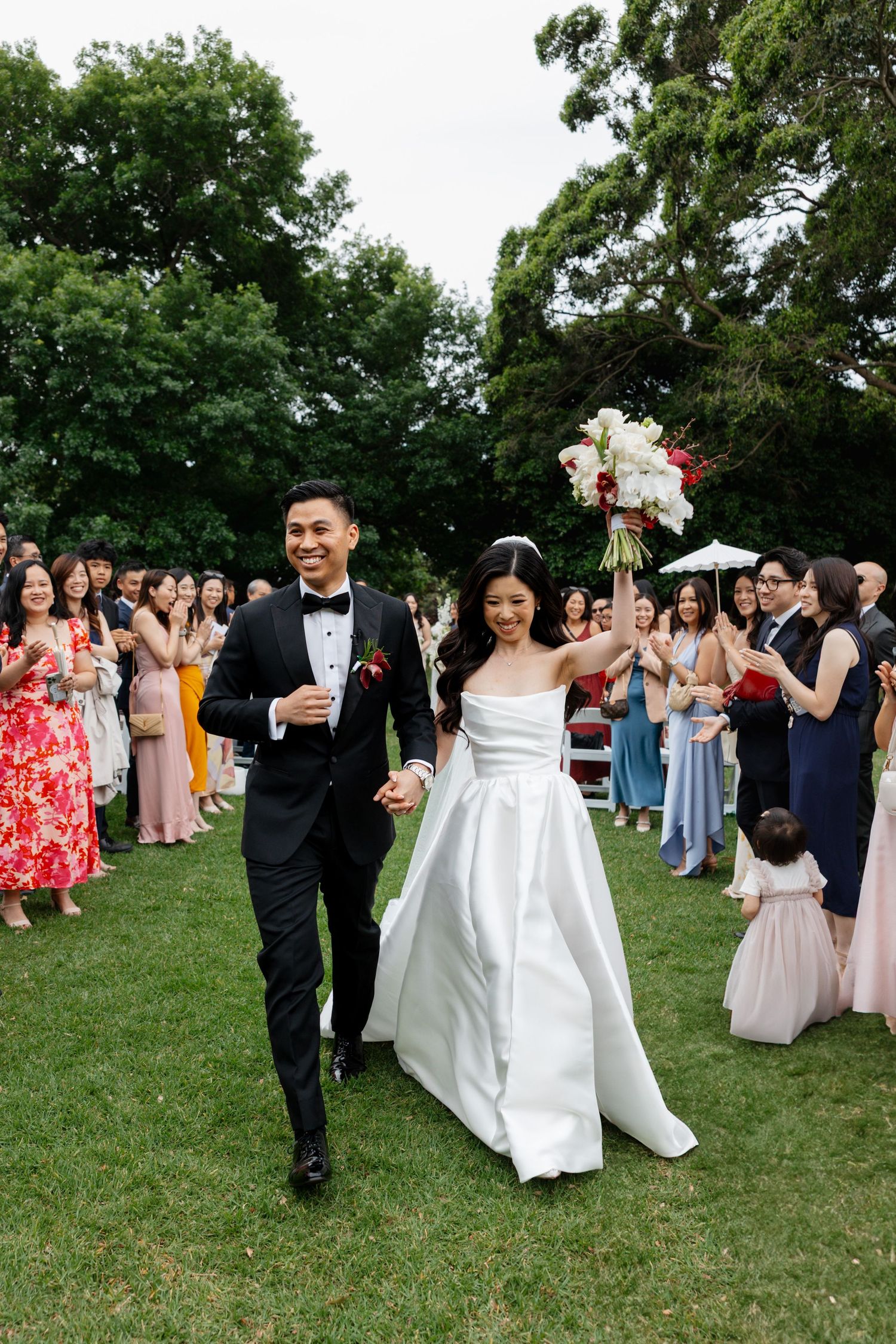 Wedding celebration on grassy lawn with guests in colorful attire.