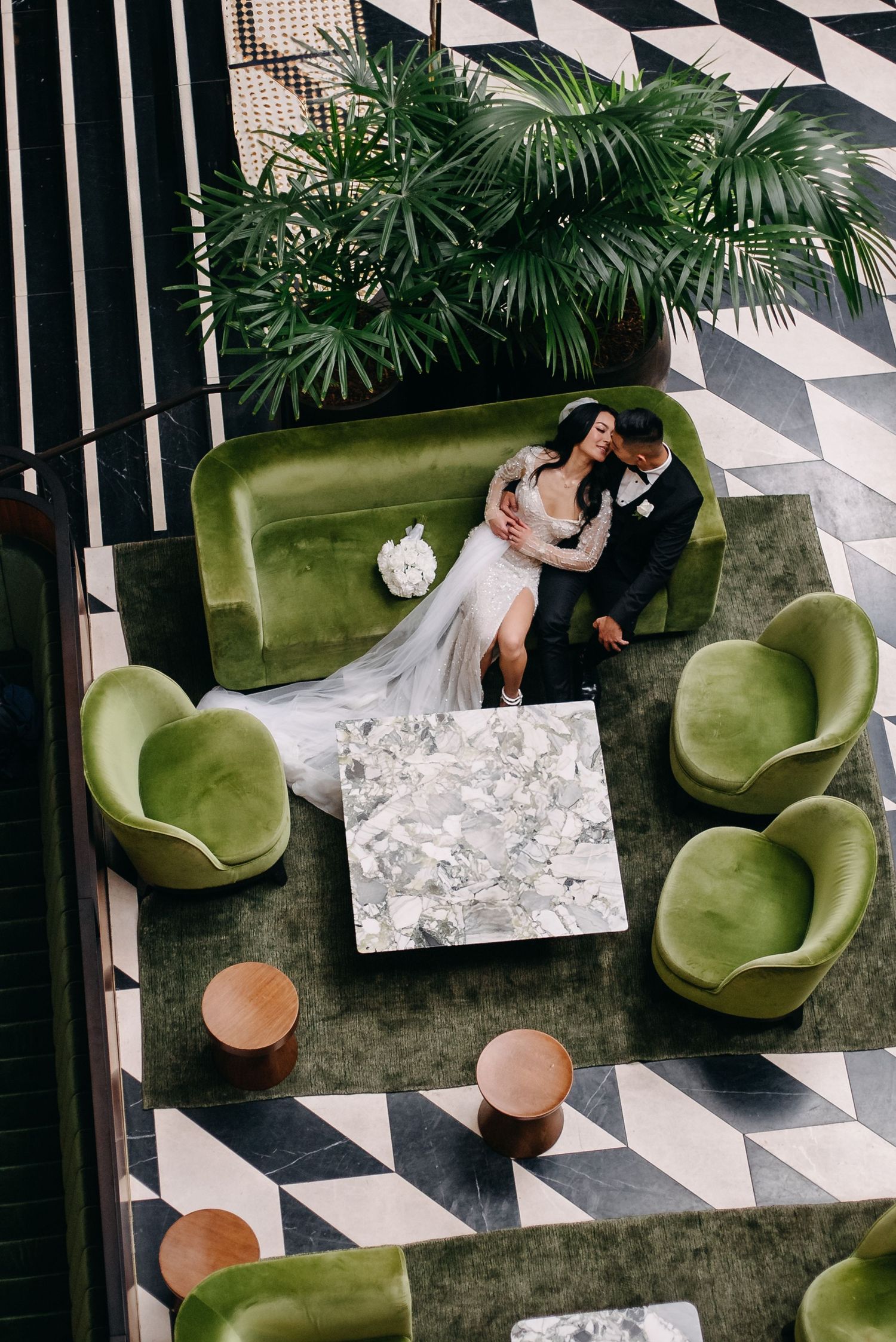 Modern lounge area with green velvet chairs and geometric floor pattern.
