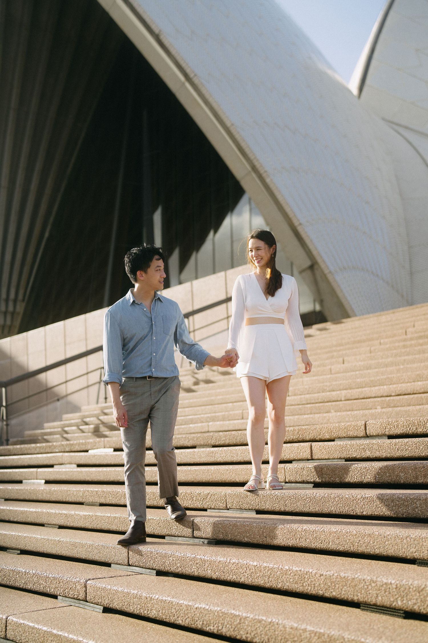 A couple playfully climbs the Sydney Opera House steps together.
