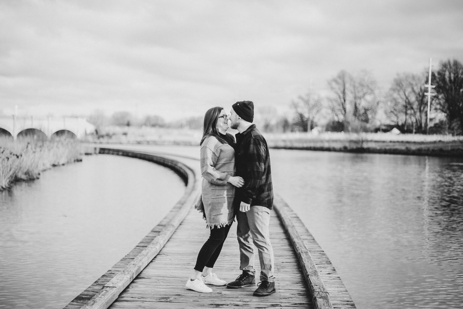 A couple looking at each other on a boardwalk bridge over a marsh