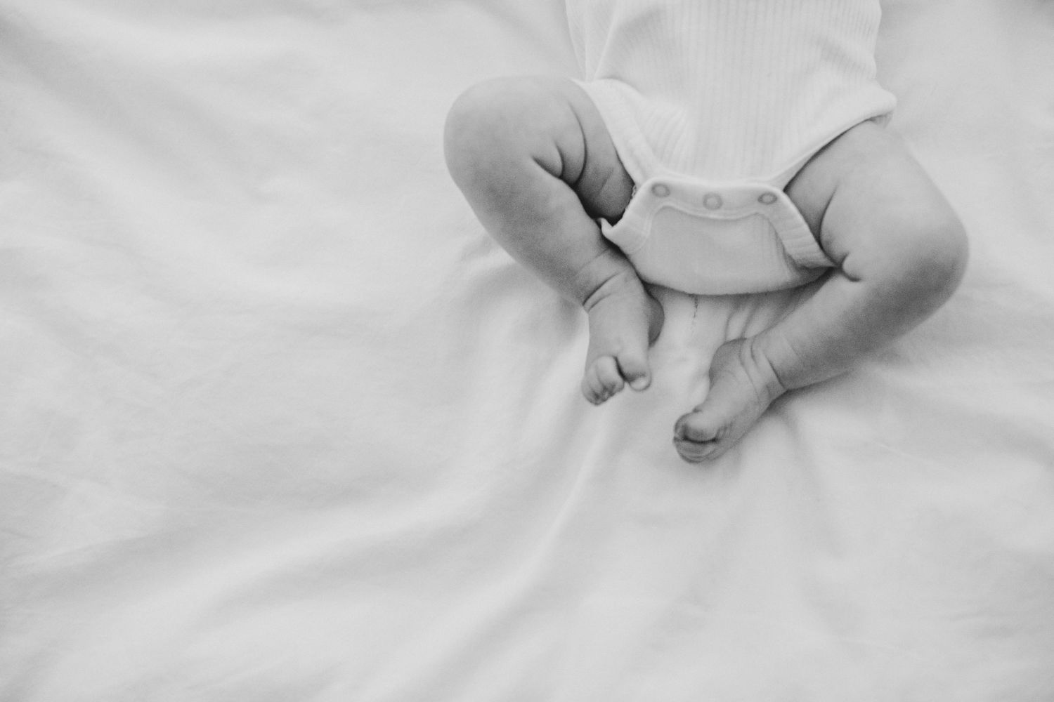 A newborn's scrunched legs on a bedsheet.